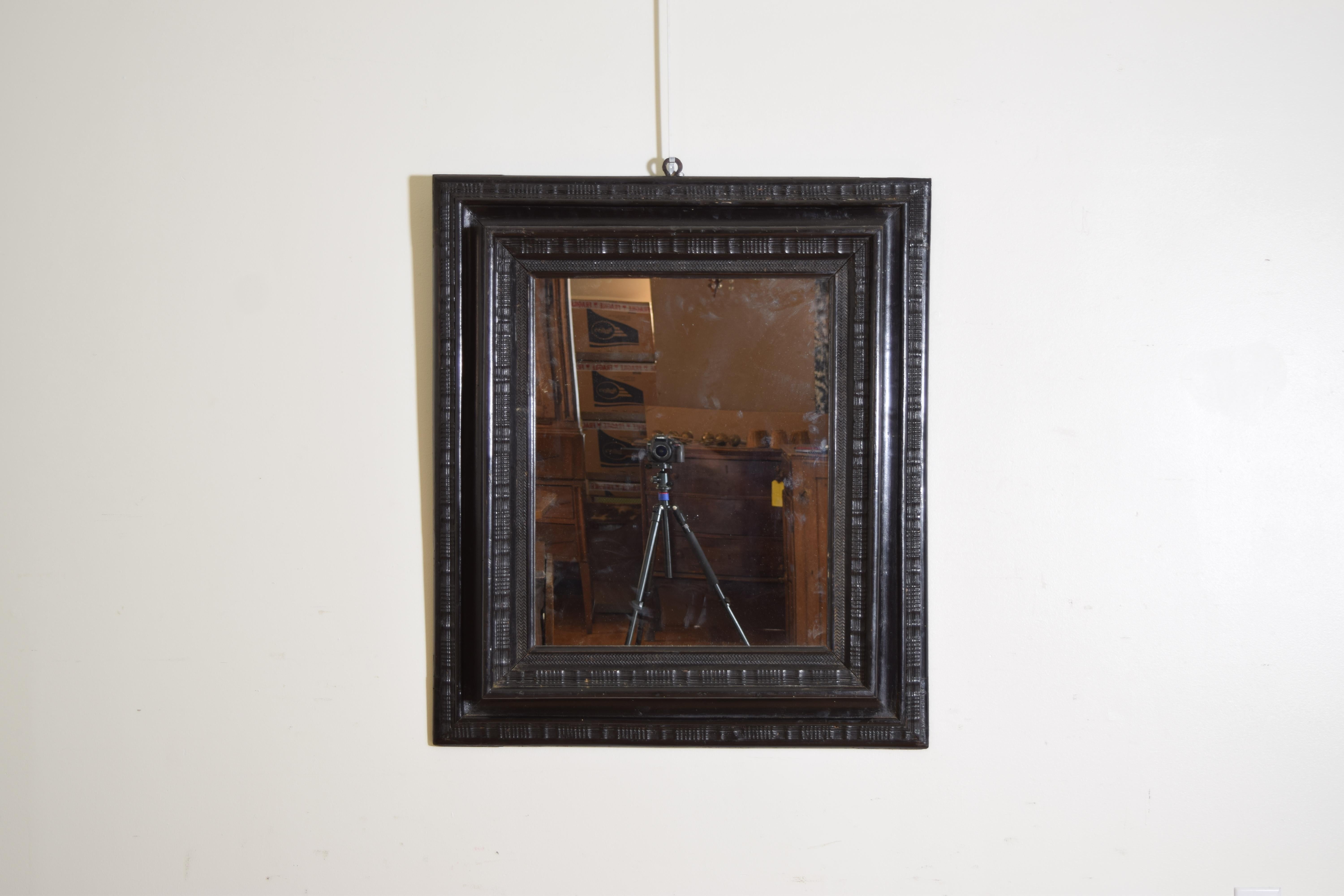 The molded edge frame with various levels of carving and deep central scoop, the inner rabbet carved in a zig-zag pattern, now fitted with modern 1/4” mirrorplate