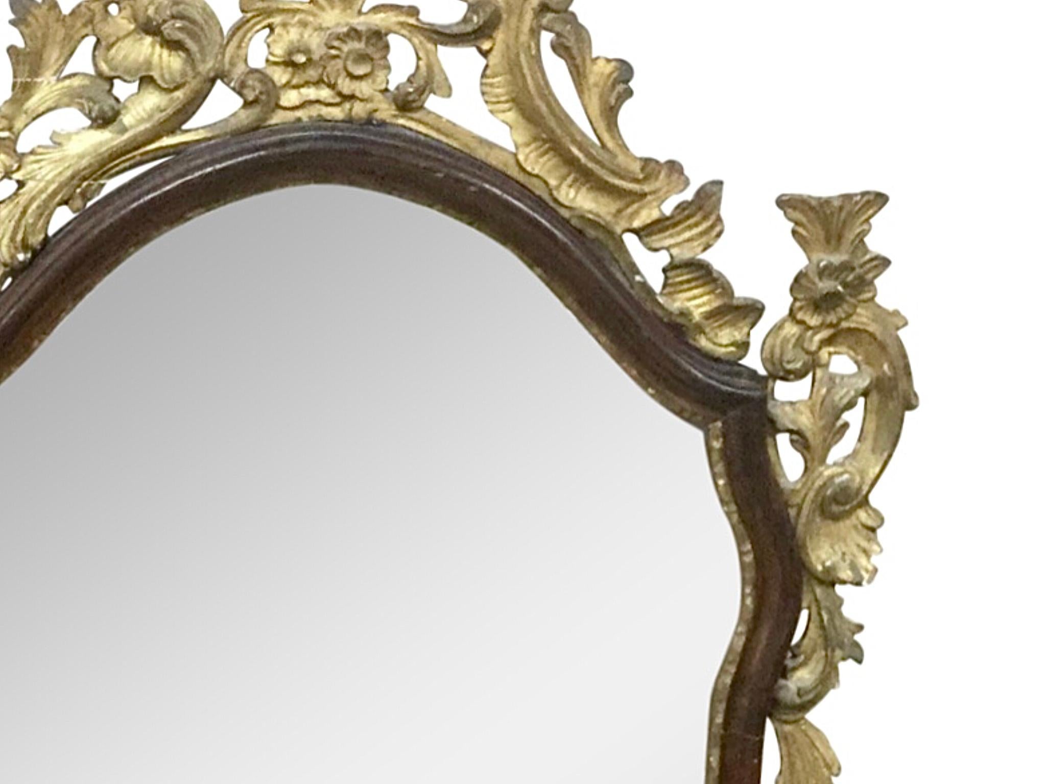 Beautiful Italian Baroque Style ebonized and carved giltwood framed mirror. Carved with floral giltwood details to the crown. The mirror bordered by an ebonized wood frame. Late 19th century.