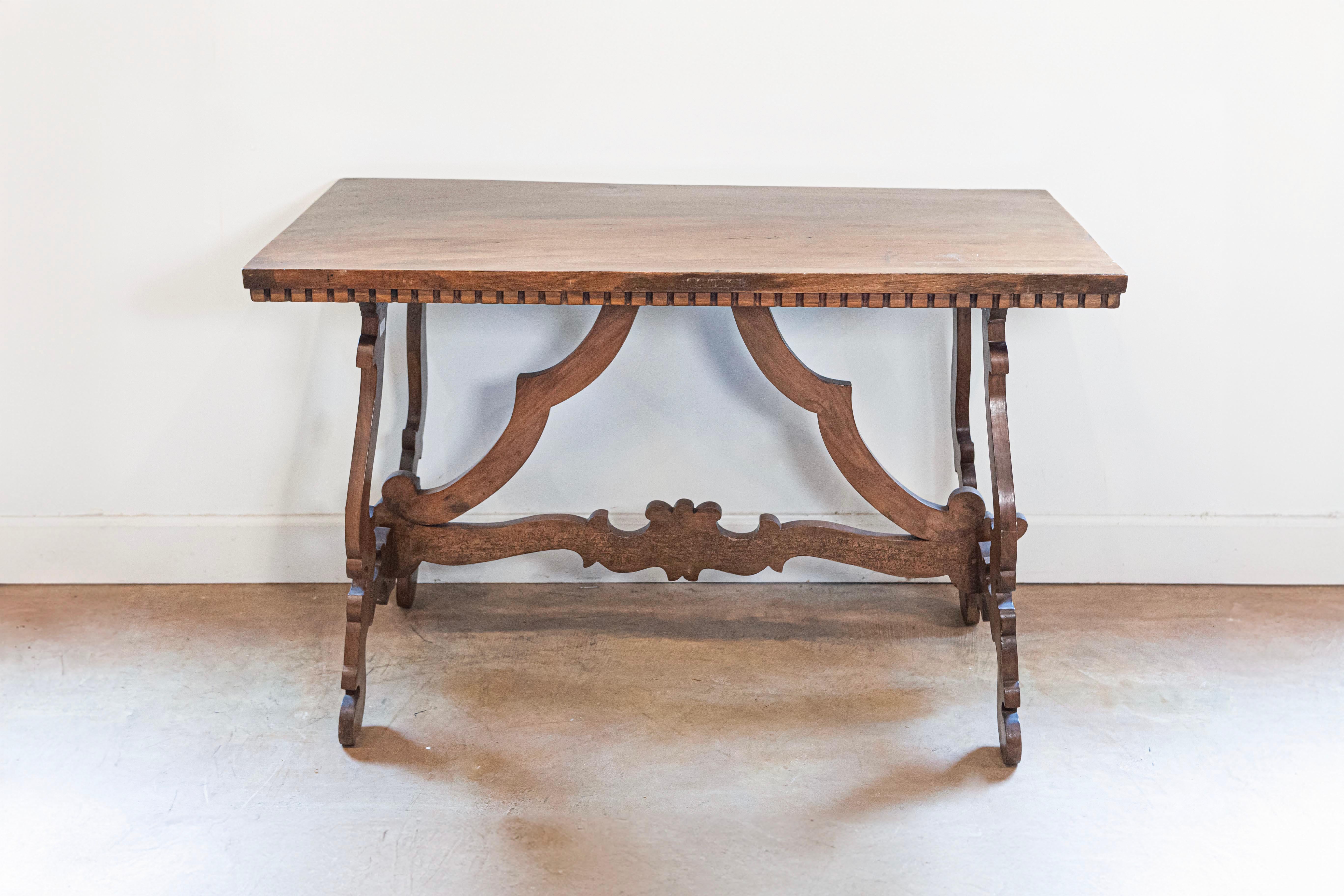 An Italian Baroque style Fratino walnut console table from the 20th century, with dentil molding, lyre-shaped base and carved stretchers. Created in Italy during the 20th century, this Fratino walnut console table features a simple rectangular top