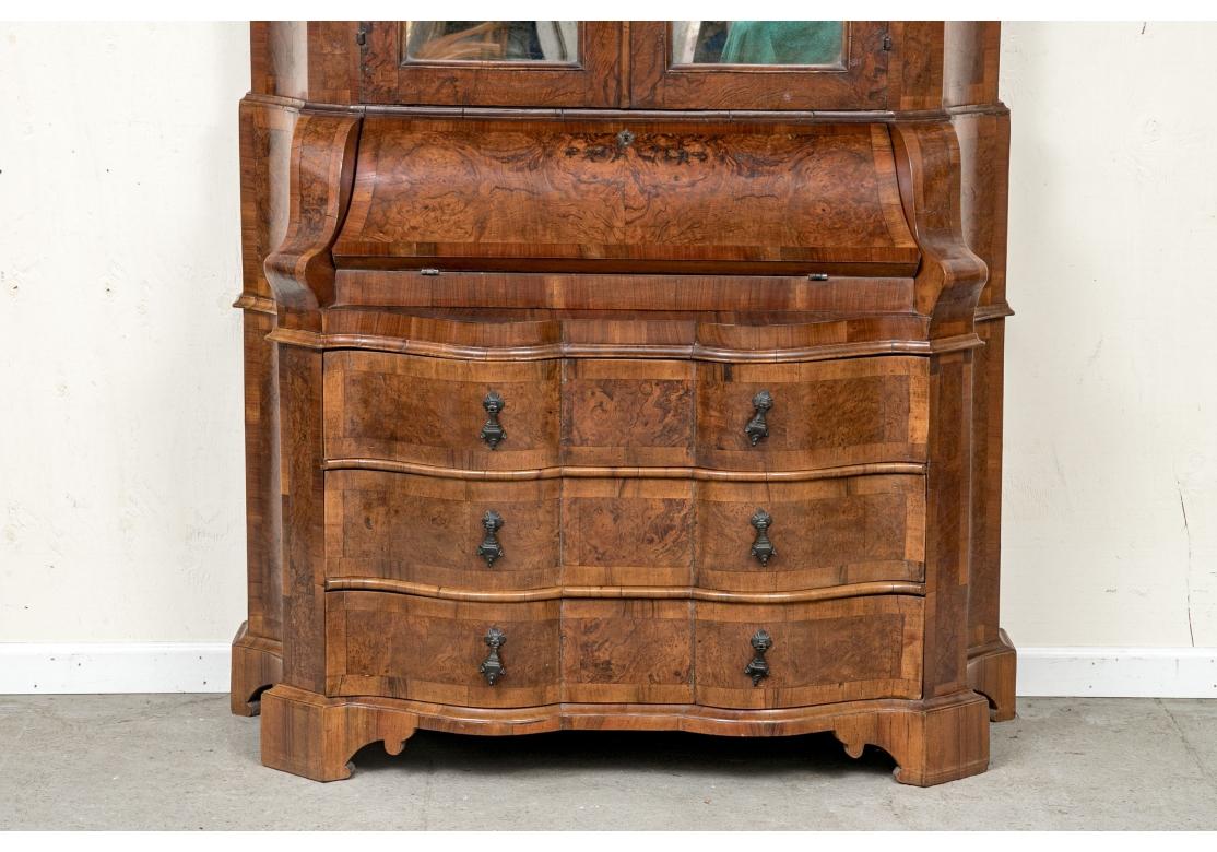 A fine Italian baroque burl walnut secretary desk with a cartouche form mirrored panel beneath a deep scrolled pediment top and above two mirrored doors. The doors with a interior wood latch on left side open to reveal two removable shelves. The