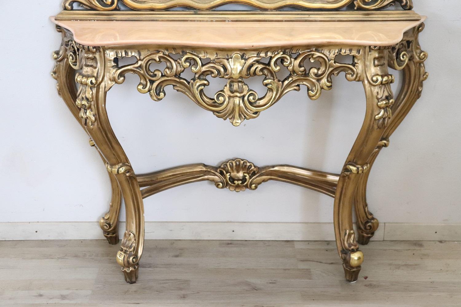 Italian baroque style console table 1930s. The console is made of solid carved wood with many curls and swirls of decoration. The wood is completely gilded and increases the importance of this console. Perfect to be placed even in representative