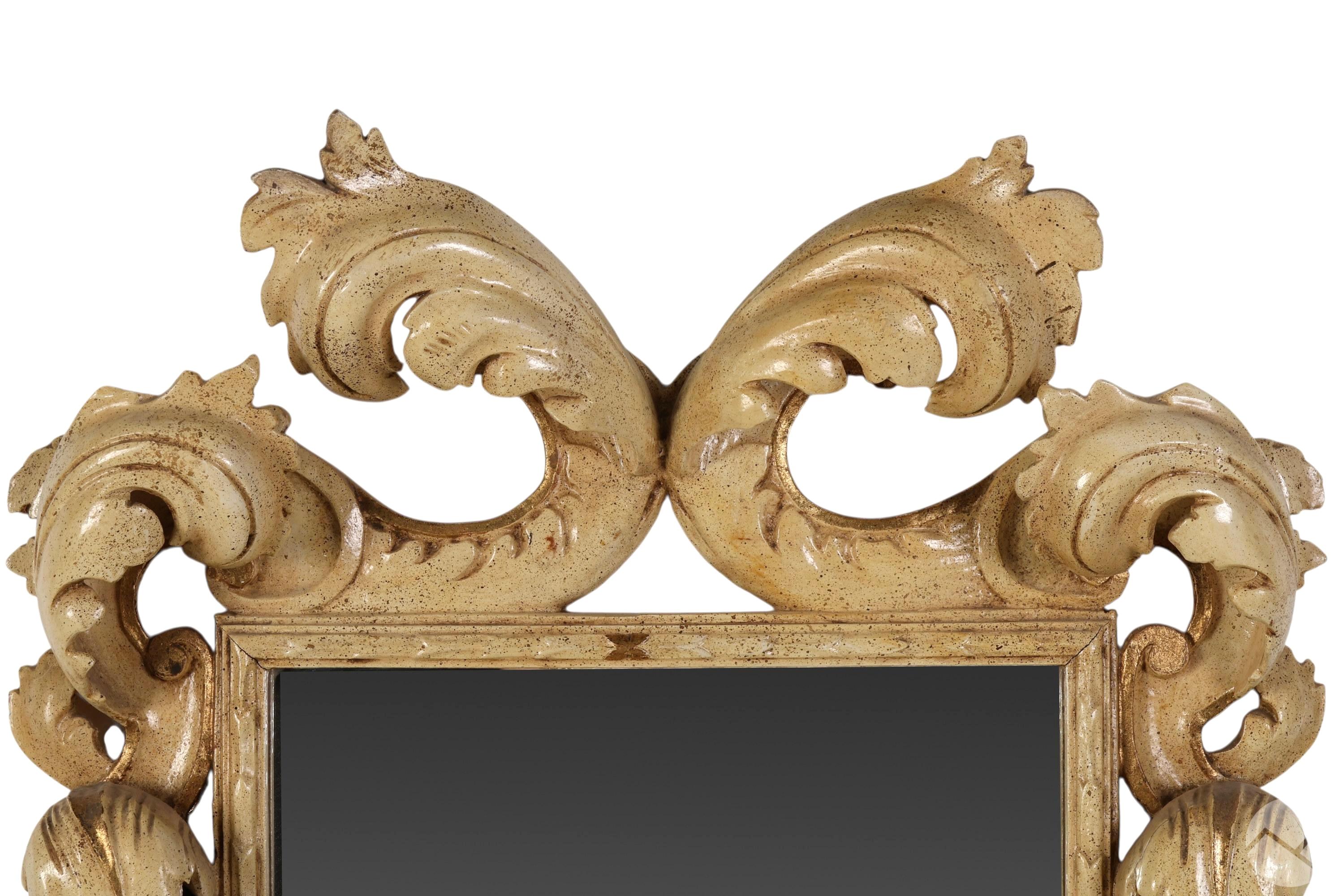 Espejo de Madera Tallada Estilo Hollywood Regency Barroco Italiano Siglo XIX. El marco del espejo presenta un ornamentado diseño de volutas tridimensionales que desprende opulencia, mientras que el profundo tallado en relieve crea profundidad y