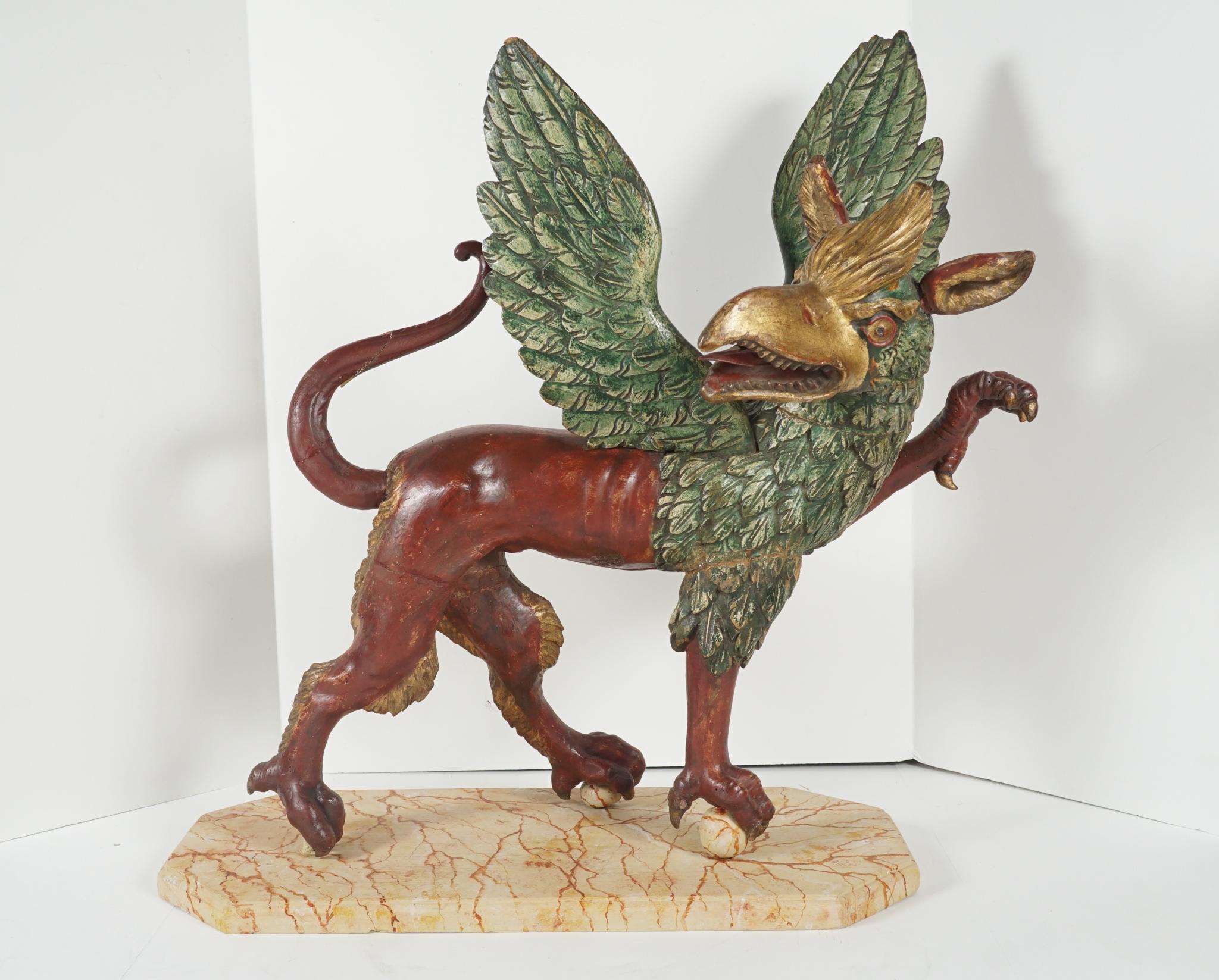 This large 18th century figure of a dramatic and animated Griffon was made in Italy in the mid-18th century. Carved in great detail then gessoed, painted and gilded the figure stands with one claw raised while two others grip balls. The base