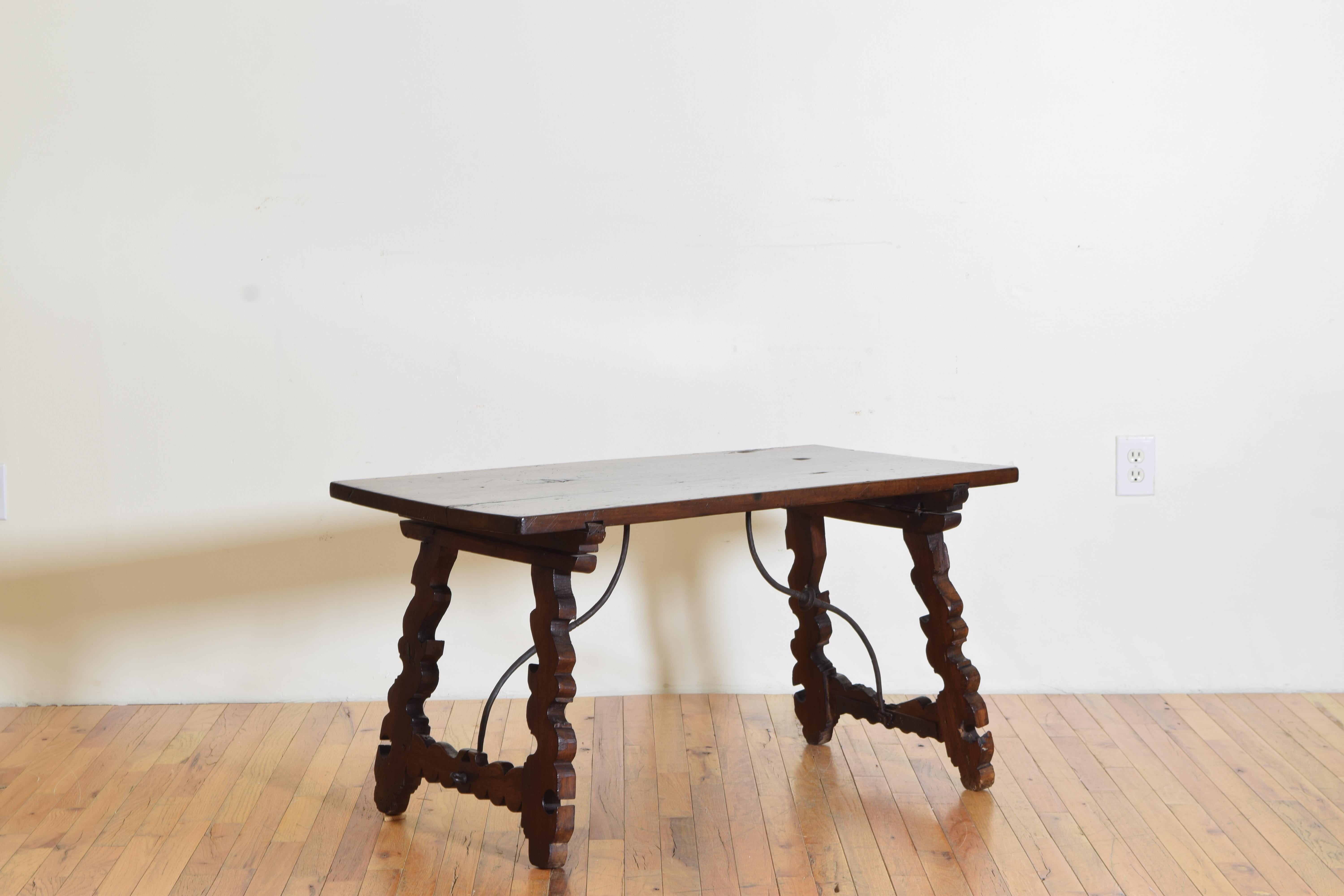 Often called lyre tables this one is of coffee table size, likely constructed from antique elements, the rectangular top raised on carved trestle supports joined by iron stretchers.