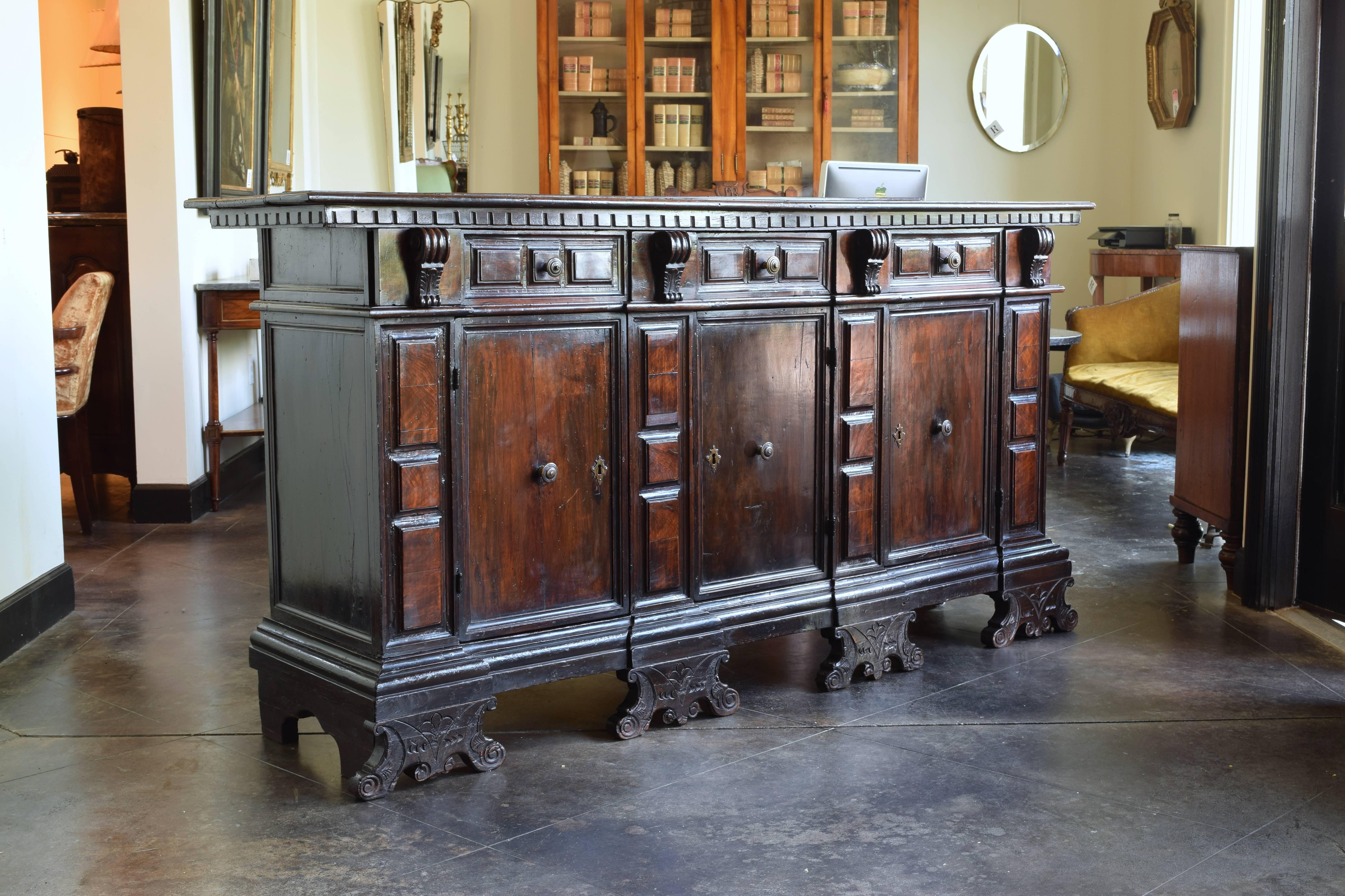 From Padova in Northern, Italy, constructed of solid walnut and pinewood as secondary, the rectangular top with molded edge atop a conforming case housing seven drawers over three doors, the doors panelled with walnut veneers, raised on a plinth