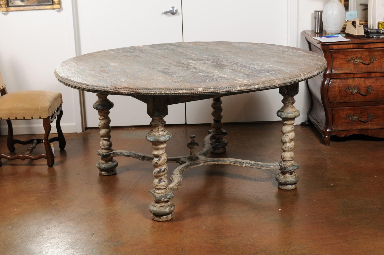 An Italian Baroque style painted dining table from the 19th century, with carved trim and barley twist base. This exquisite painted, 19th century dining table features a circular scraped top, adorned with a delicately carved trim. The table is