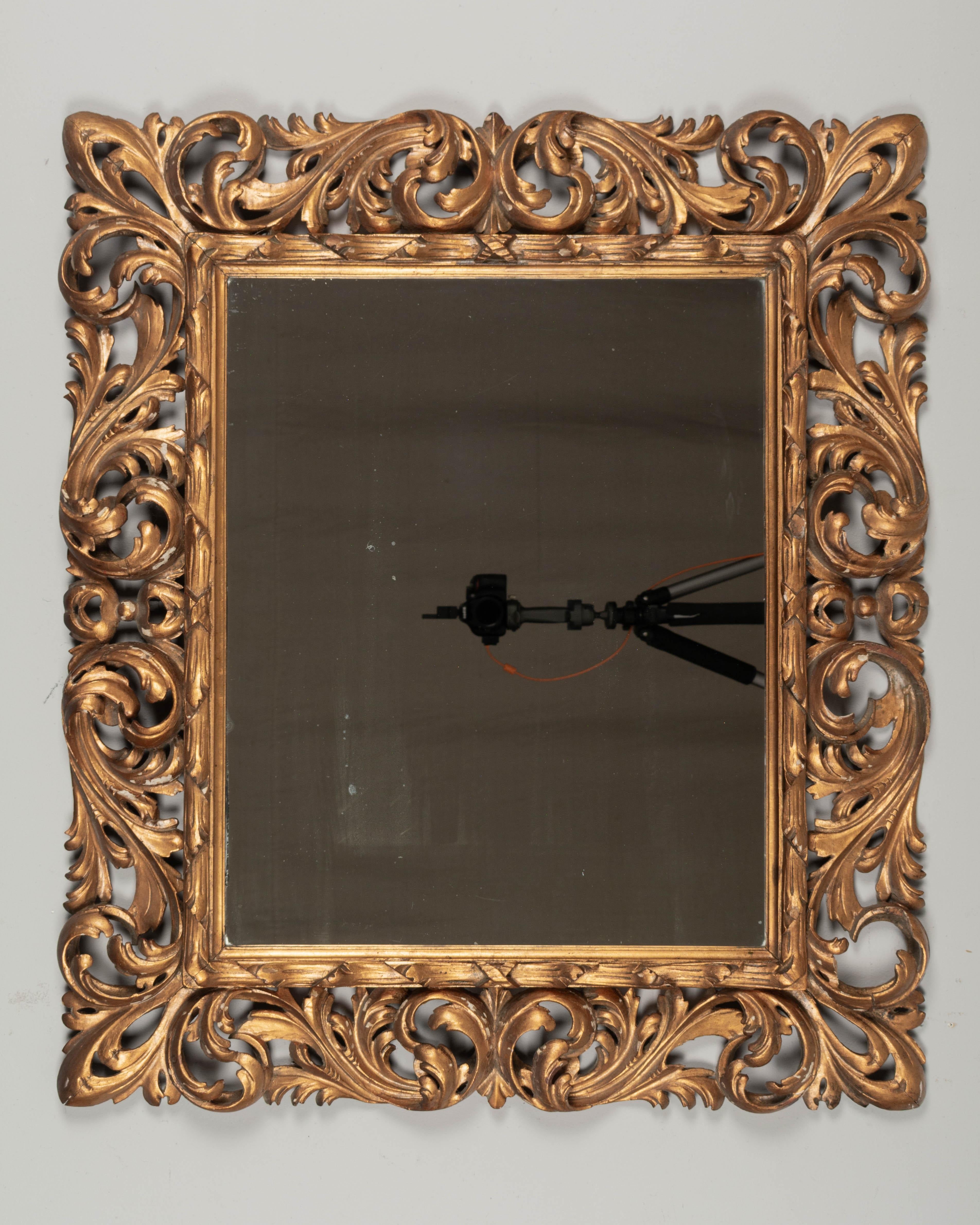 Ein italienischer Barockspiegel aus vergoldetem Holz mit geschnitzten Akanthusblättern. Warme Vergoldung mit vielen Verlusten in der Vergoldung und einigen kleineren Verlusten in der Schnitzerei. Original-Spiegel. Zum horizontalen Aufhängen
