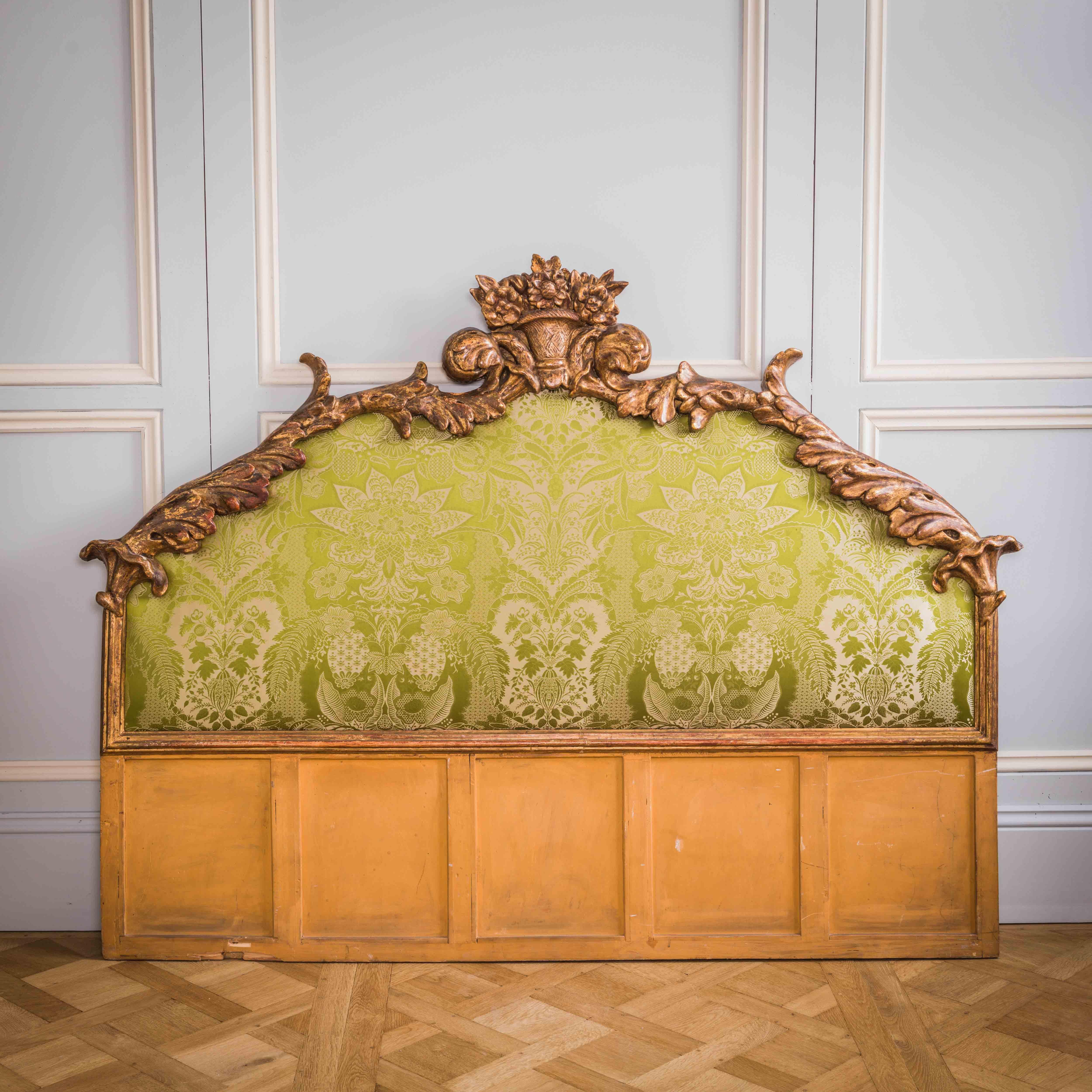 An exceptional Italian headboard in the Baroque style, Circa 1880, made of a a generously carved surround featuring acanthus leaves with a floral crest at its apex. The gilding on this piece is original with a naturally aged, deep toned patina,