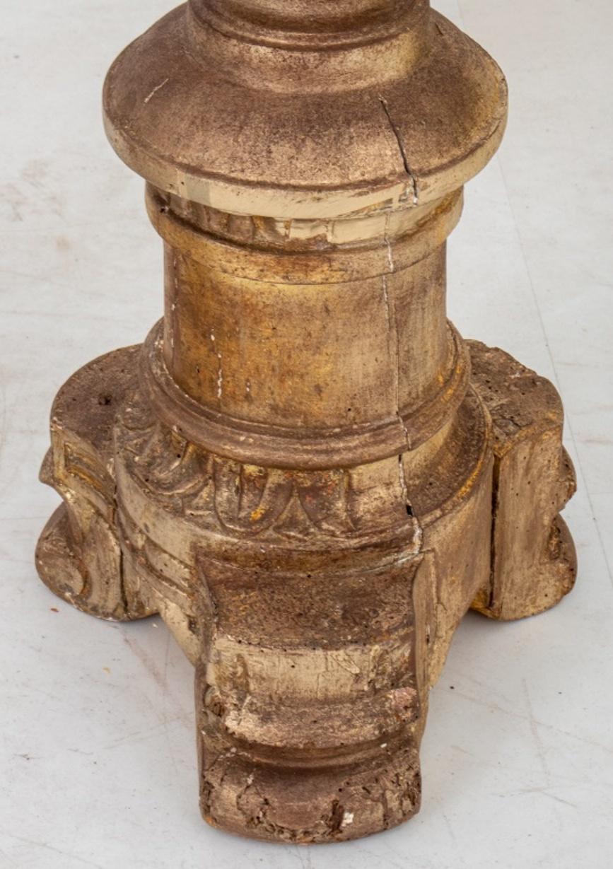 Italian Baroque style giltwood torchieres or pedestals, a pair, each with circular tops above acanthus-carved columnar supports above turned socles on tripodal volute bases.

Dimensions: 47