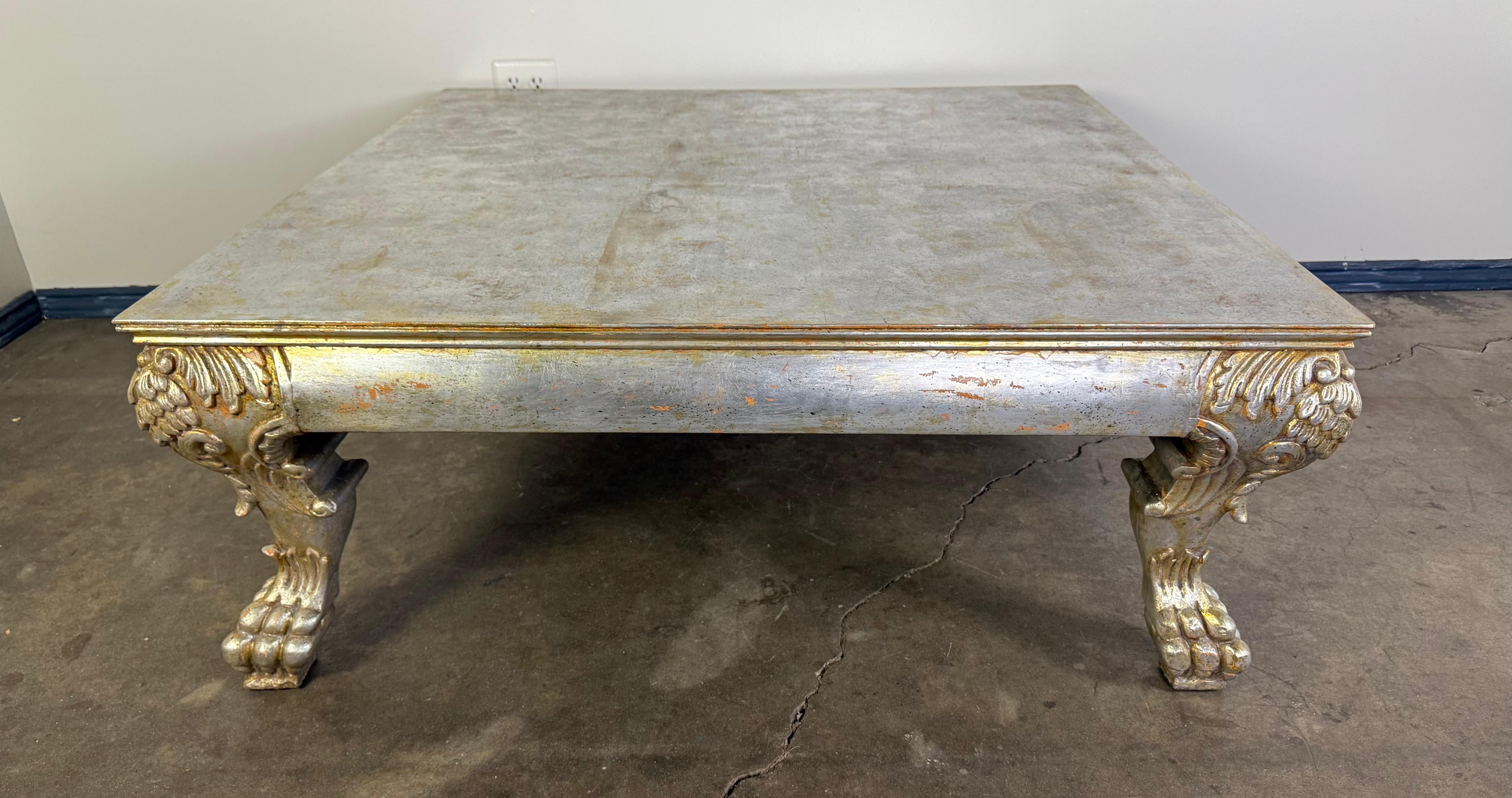 A striking Italian silvered wood coffee table, crafted in the early 20th century and richly detailed in the Baroque revival style. The rectangular top features a beautifully aged silver leaf finish with subtle gilt undertones and an intentionally