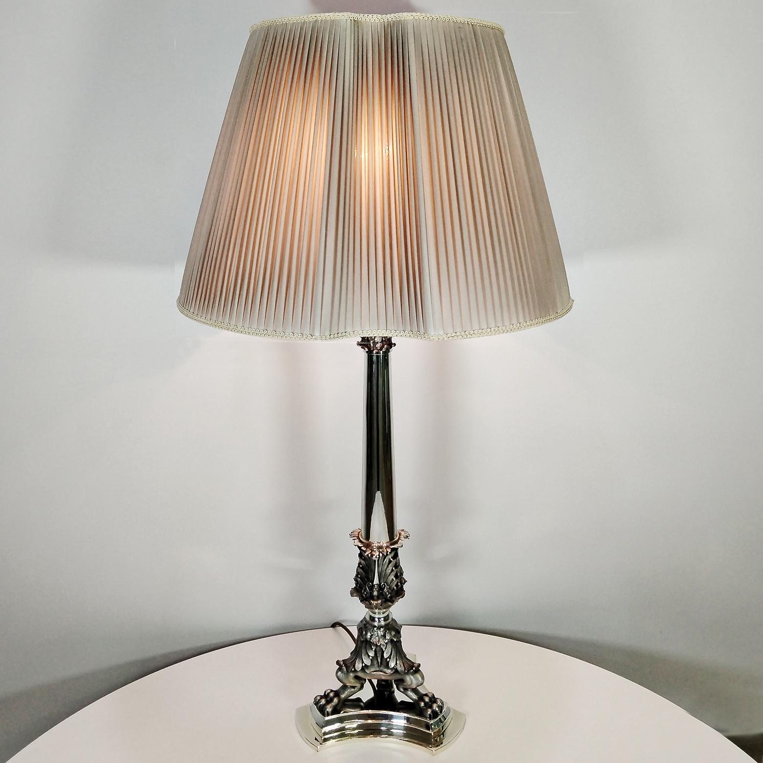 Baroque-style solid 800 silver lamp featuring a mythological figure with lion paws and a human face. The lamp has a curved double triangular base, which holds the lion paws that support the lamp shaft. The base is removable for cleaning. Above the