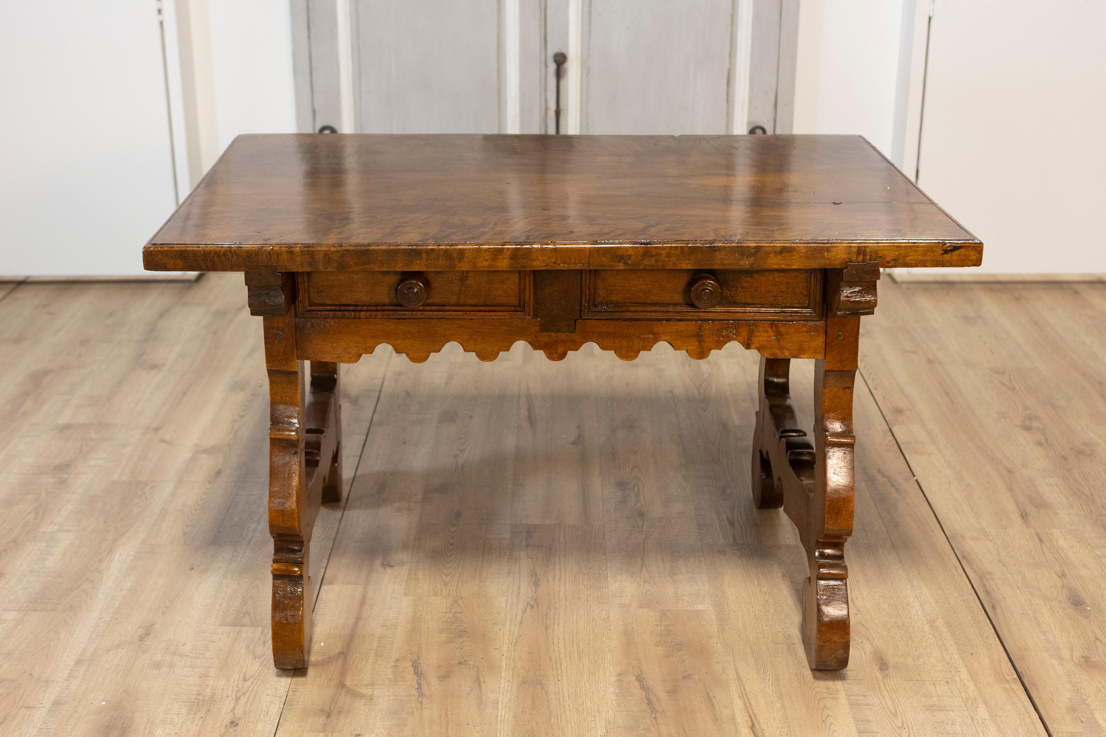 An Italian Baroque style walnut Fratino table from the 19th century with carved lyre shaped legs and two drawers. This exquisite Italian Baroque style Fratino table from the 19th century is a striking piece of craftsmanship, beautifully marrying