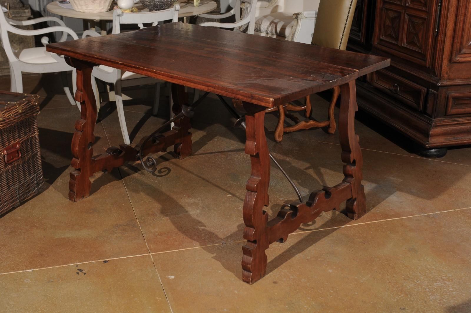 An Italian Baroque style carved walnut Fratino table from the 19th century with iron stretchers. Born in Italy during the 19th century, this exquisite walnut table features a rectangular planked top, sitting above an eye-catching Baroque style