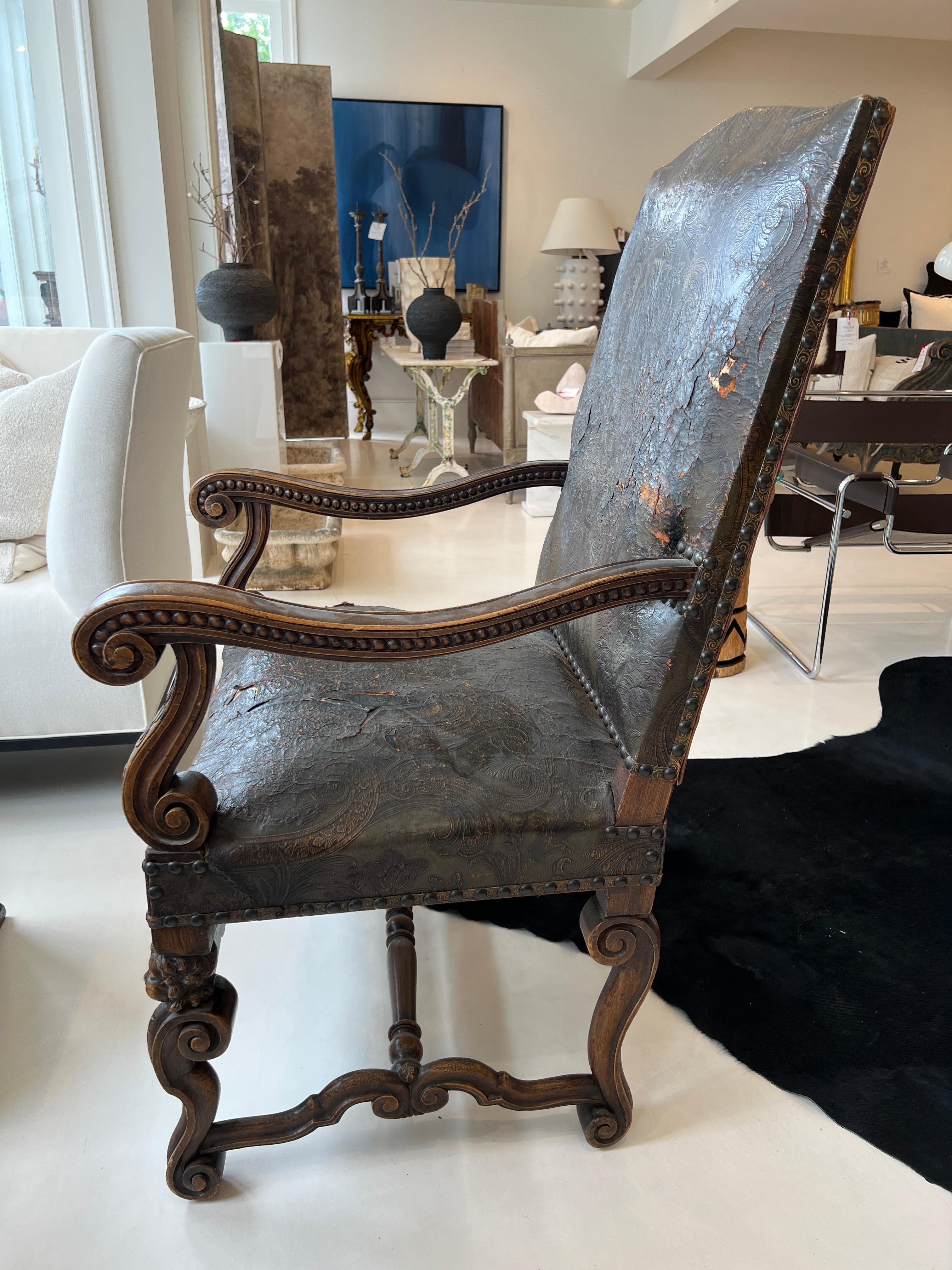 This large tooled leather and carved wood armchair has a lot to say. An imposing size is only the beginning. The winged angels blowing trumpets draw your eye towards the ornate detailing which is carved within the wood and embedded within the