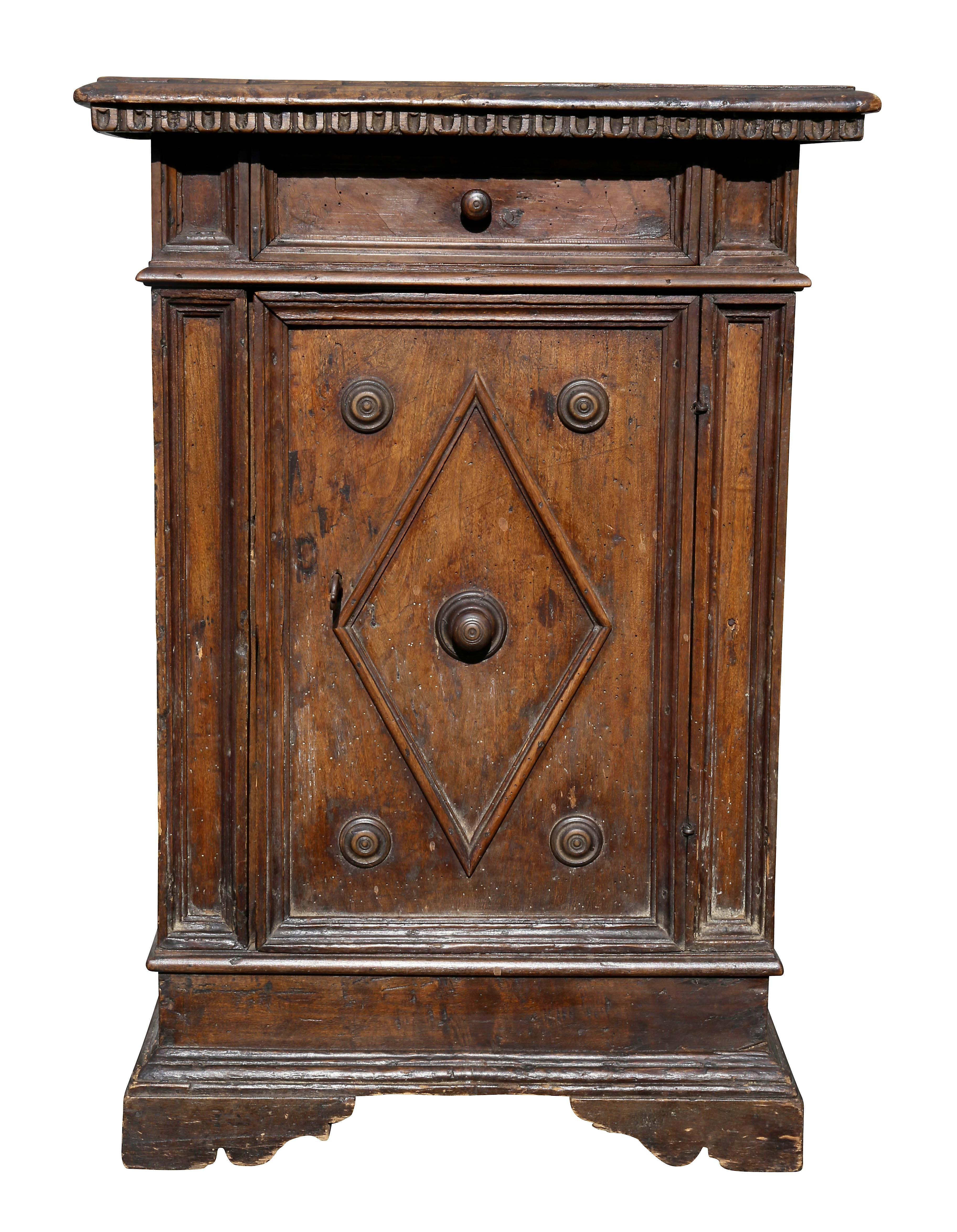 Rectangular top over a drawer and a door with a diamond shaped molding with four roundels, bracket feet.