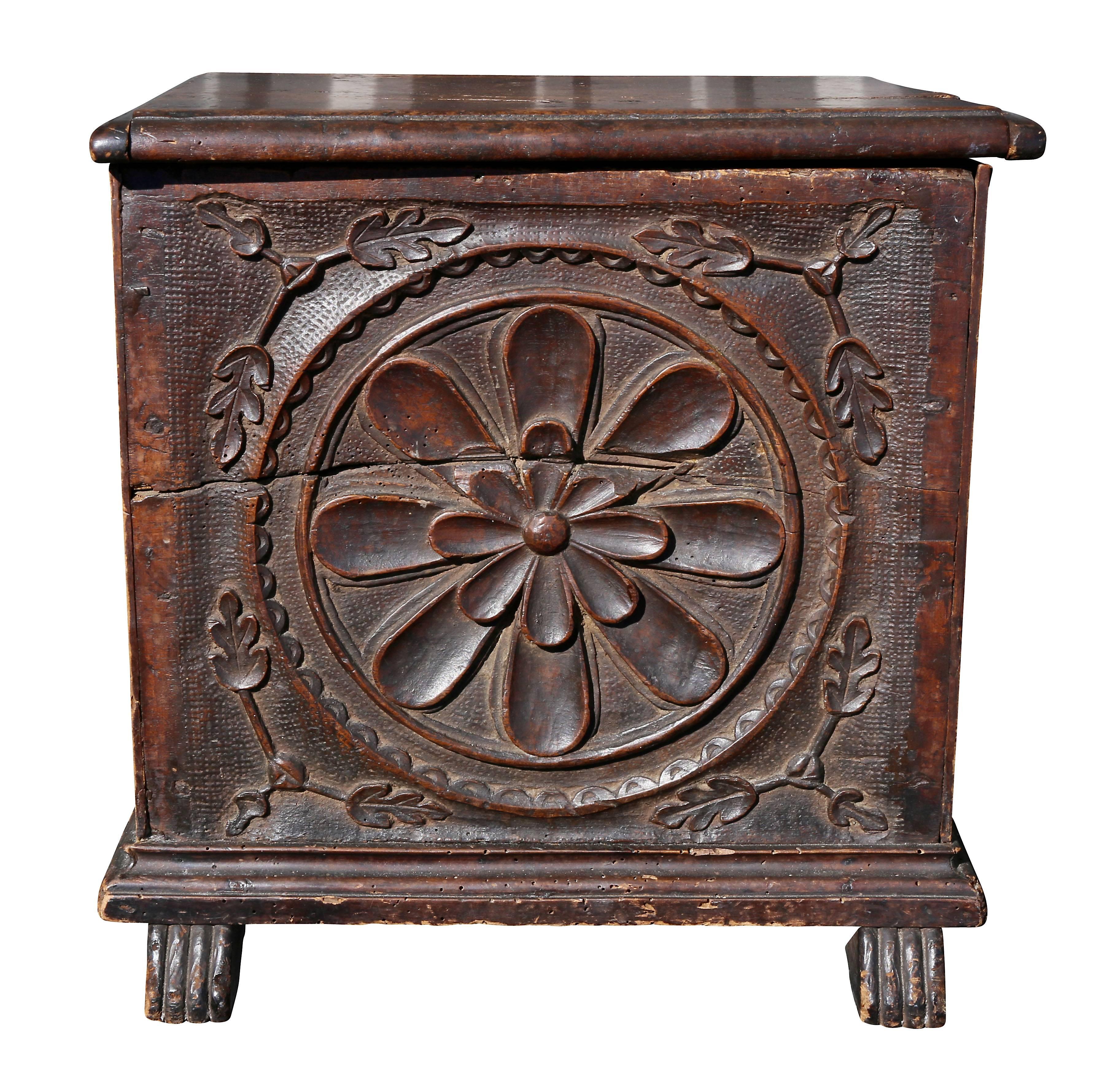 With hinged top over a panel carved with a circular floral panel surrounded by leaves, shoe feet.