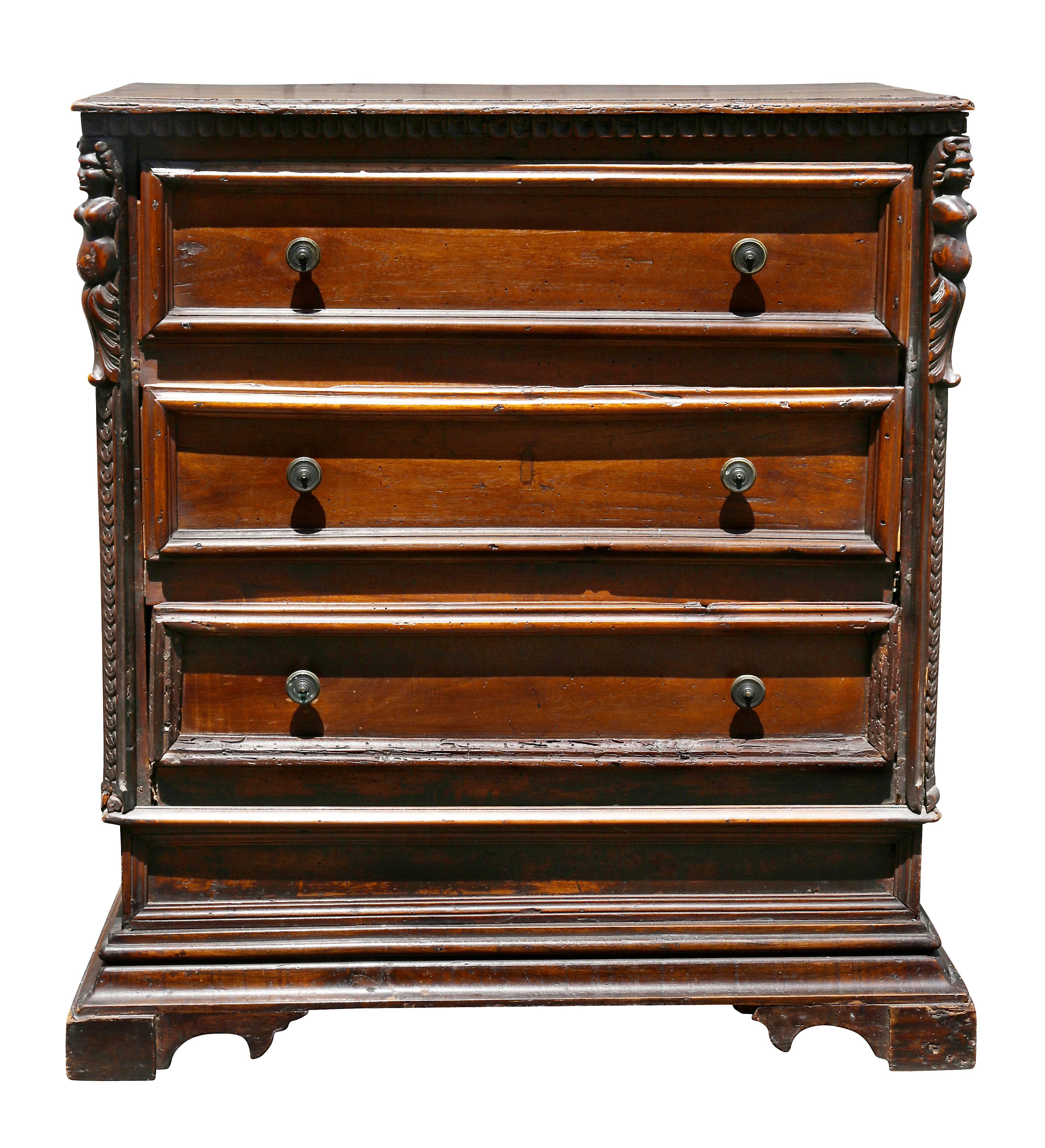 With a rectangular top over three drawers flanked by carved figures, raised on bracket feet.
