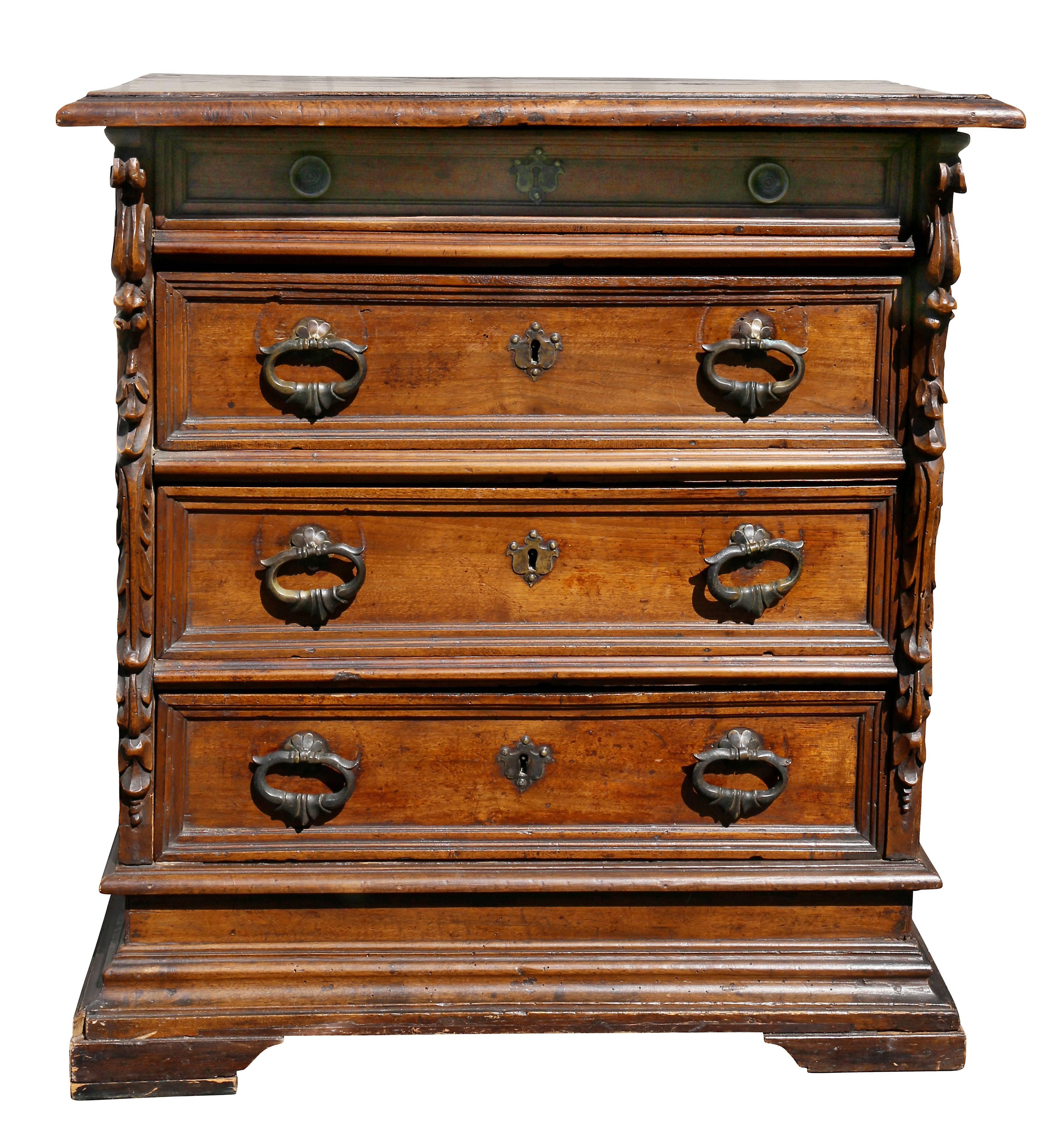 Rectangular top over four drawers flanked by carved decoration, raised on bracket feet.