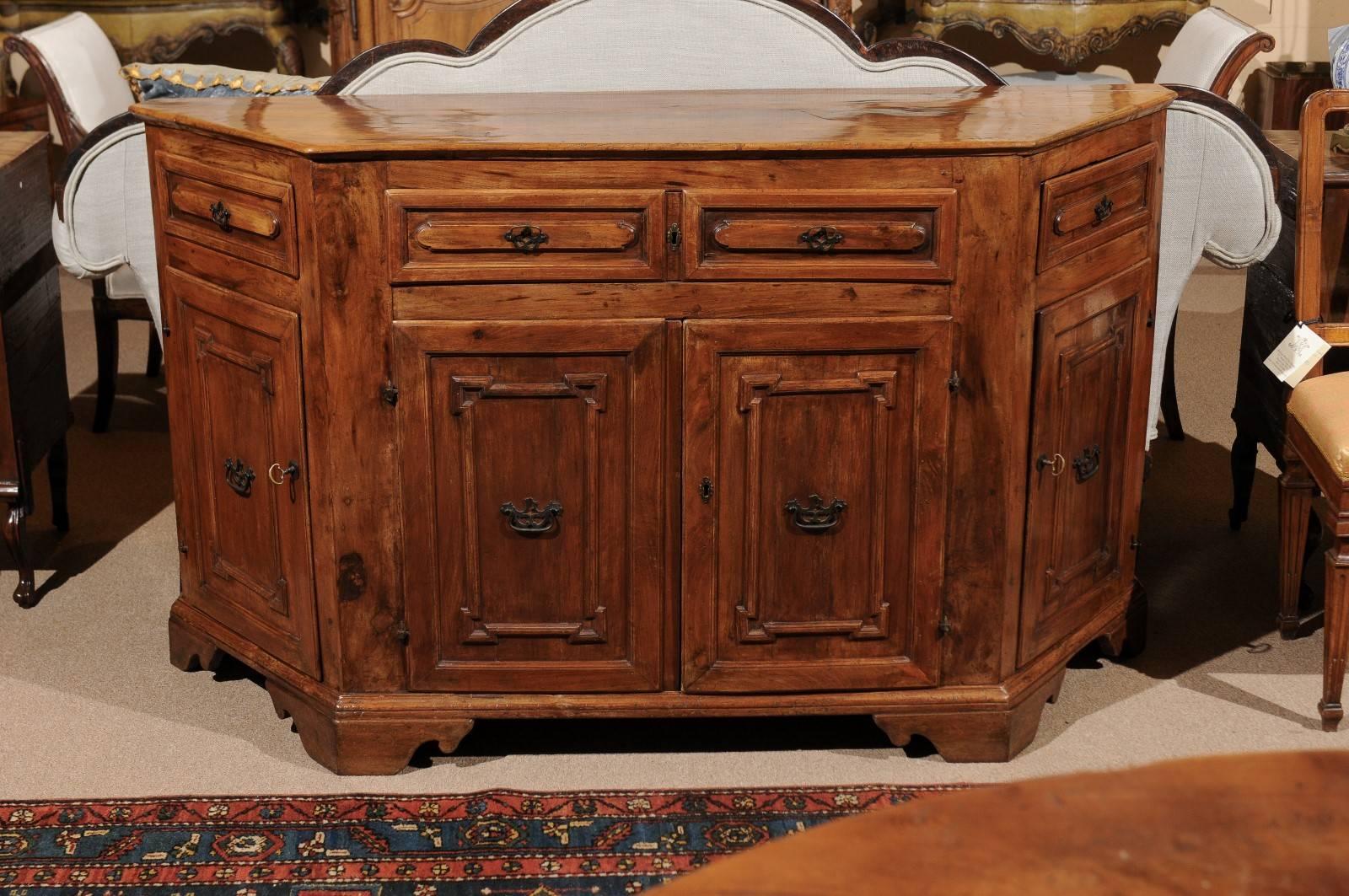 Baroque walnut credenza with canted sides, carved paneled raised drawers and carved paneled doors below. All resting on carved bracket feet.