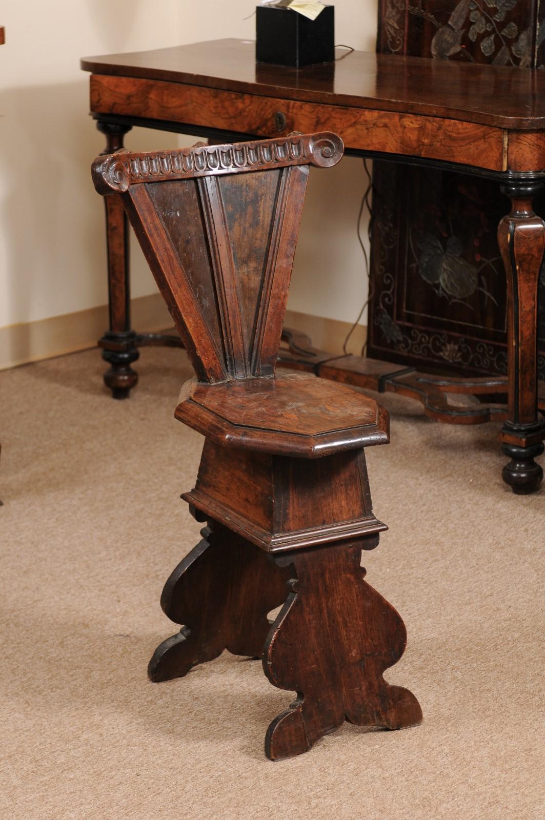 The Italian Baroque hall chair in walnut with carved triangular back with scroll detail and octagonal formed seat.