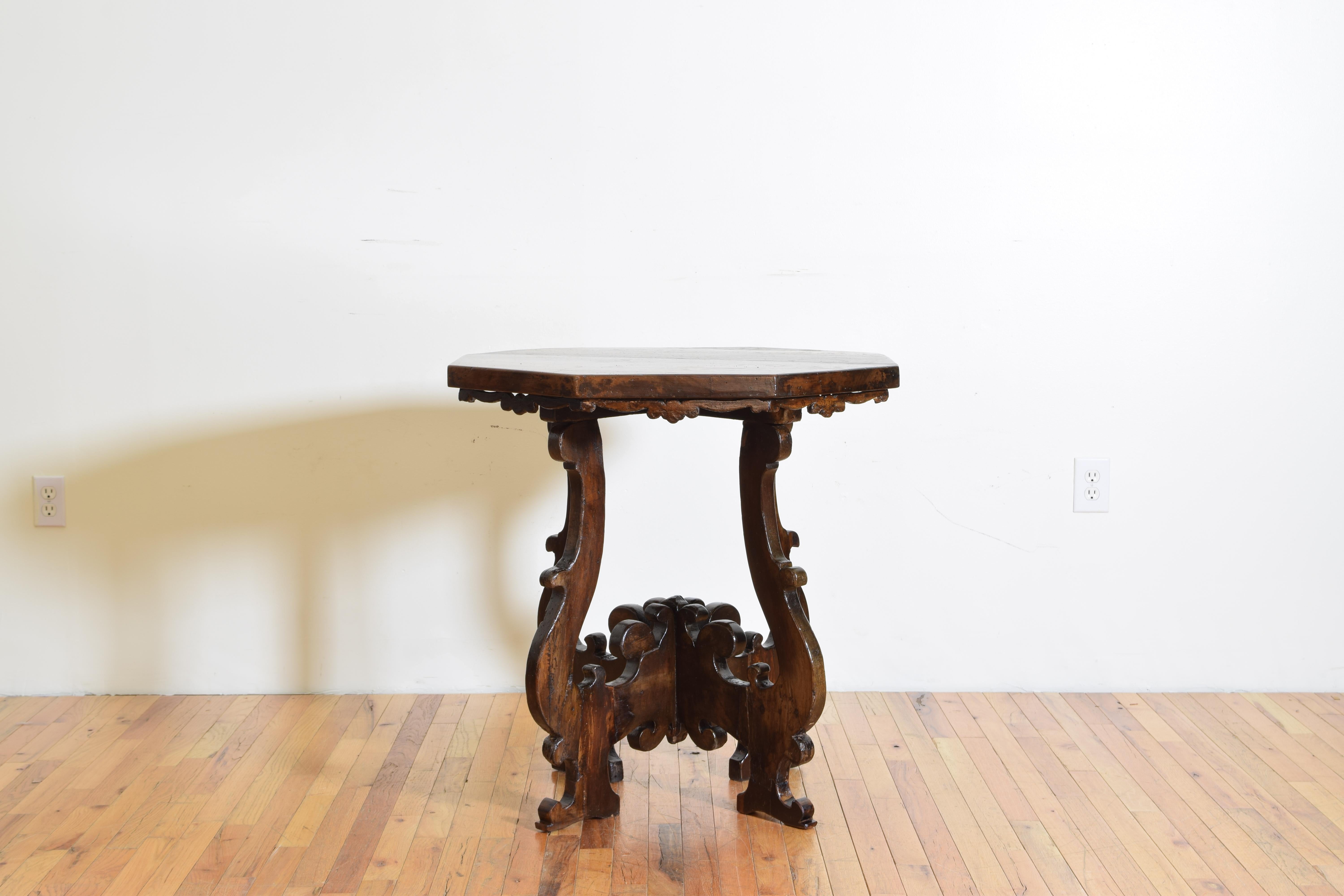 The octagonal top with a carved apron raised on scrolling legs joining in the center to form a large finial, resting on shaped bracket feet.
 