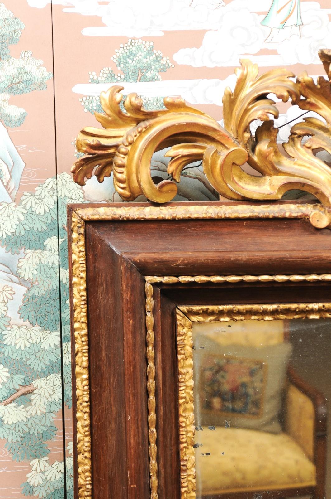 A late 17th century Italian Baroque walnut and parcel gilt mirror featuring carved giltwood acanthus leaf crest above rectangular walnut and parcel molded frame.