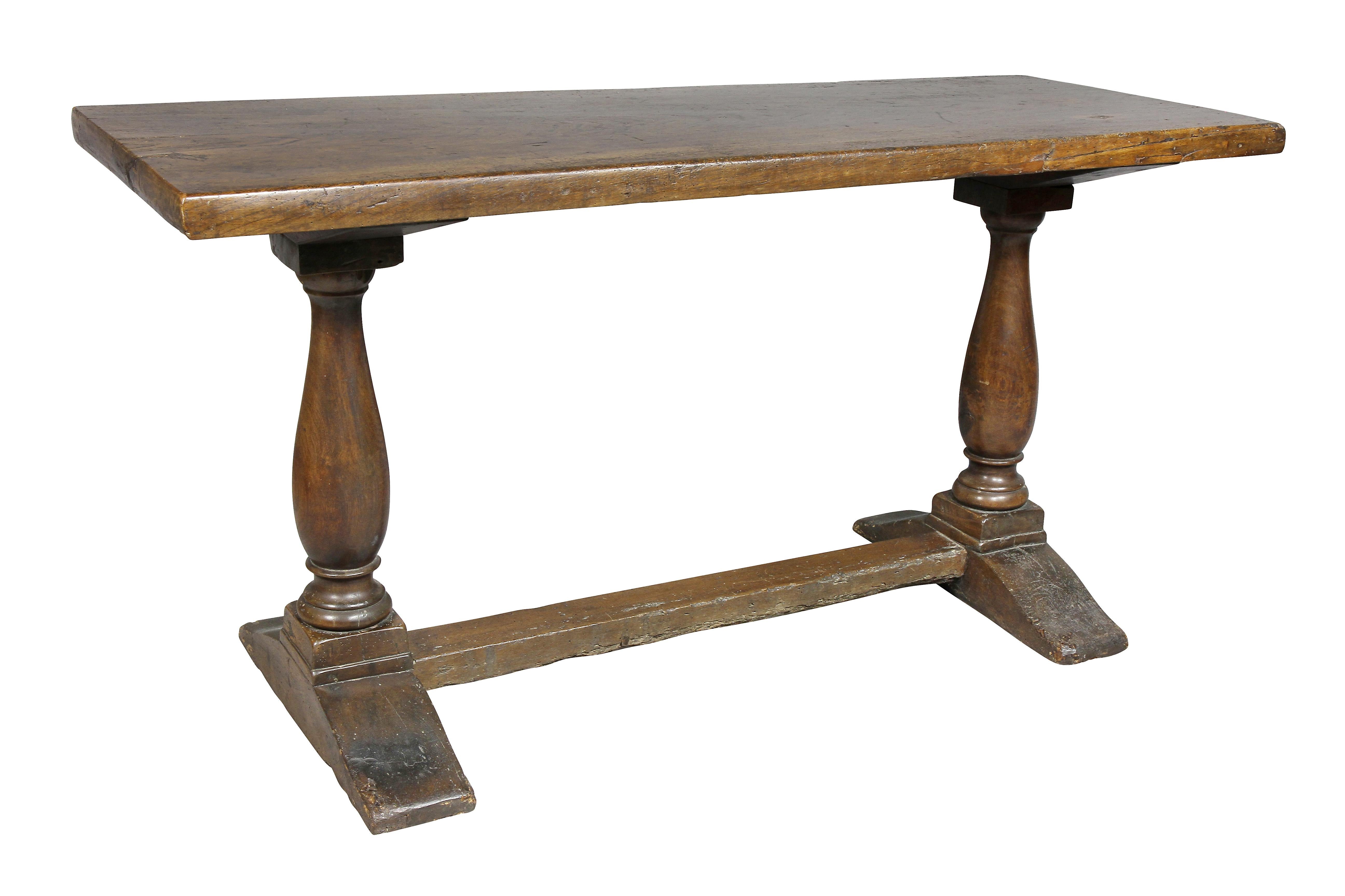 Rectangular single board top over a trestle form base comprising two turned columns joined by a stretcher, shoe feet.
