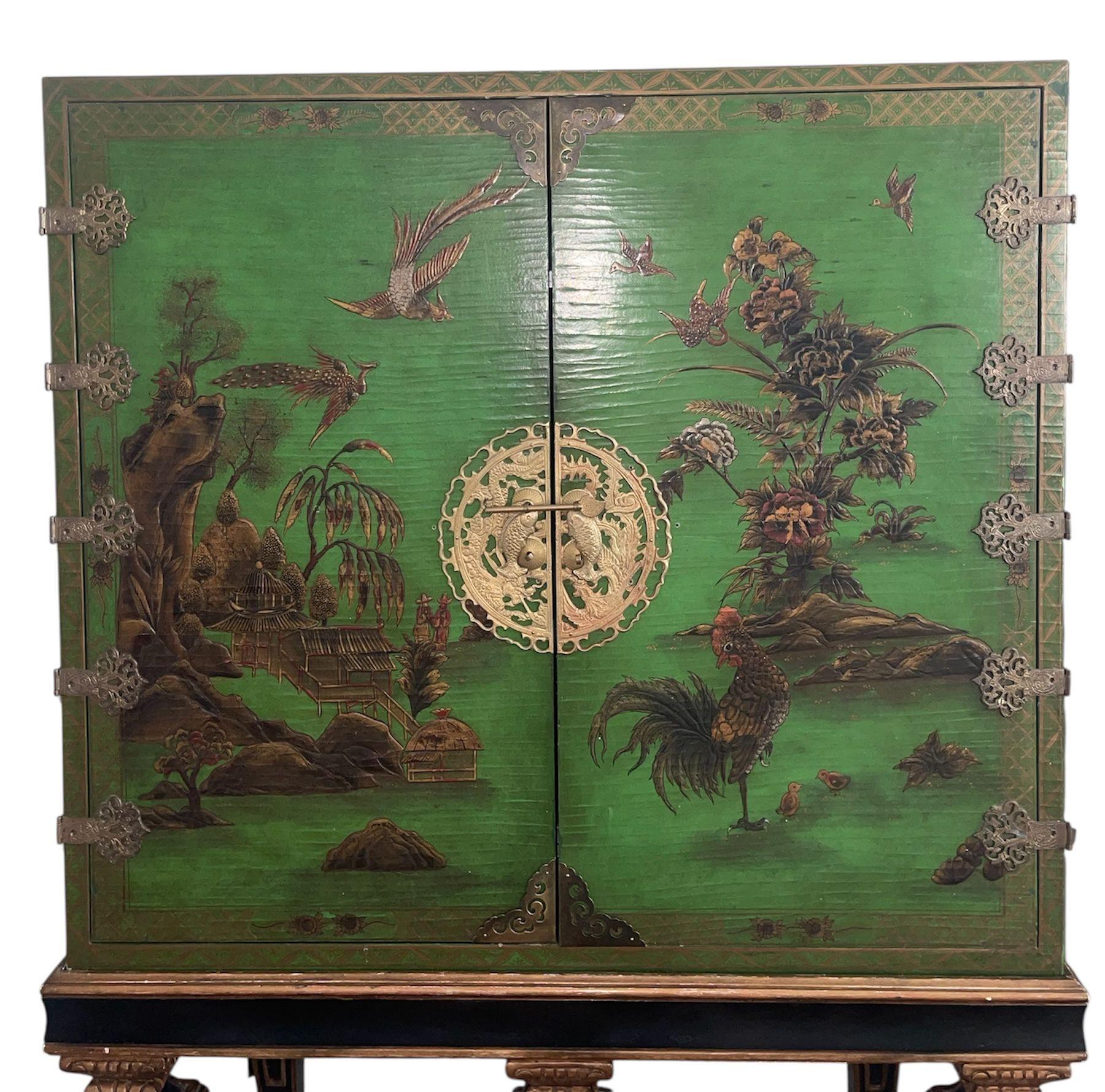 Ein auffälliger, aufwändig mit grüngrundigem Chinoiserie-Lack verzierter Standschrank im Stil des Barockrevivals. Die Doppeltüren sind mit romantischen Landschaften bemalt - Seesterne, Singvögel, blühende Sträucher, Felsen und Pavillons -, die von