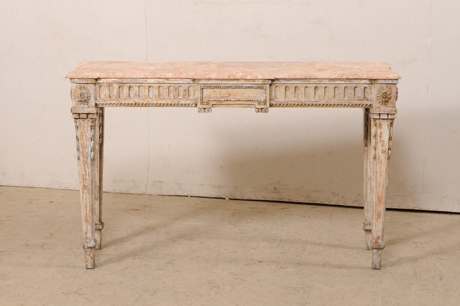 An Italian nicely carved wood console table, with its original marble top, from the 19th century. This antique table from Italy features its original coral colored marble top, which is primarily long, and rectangular with a subtle break-front design
