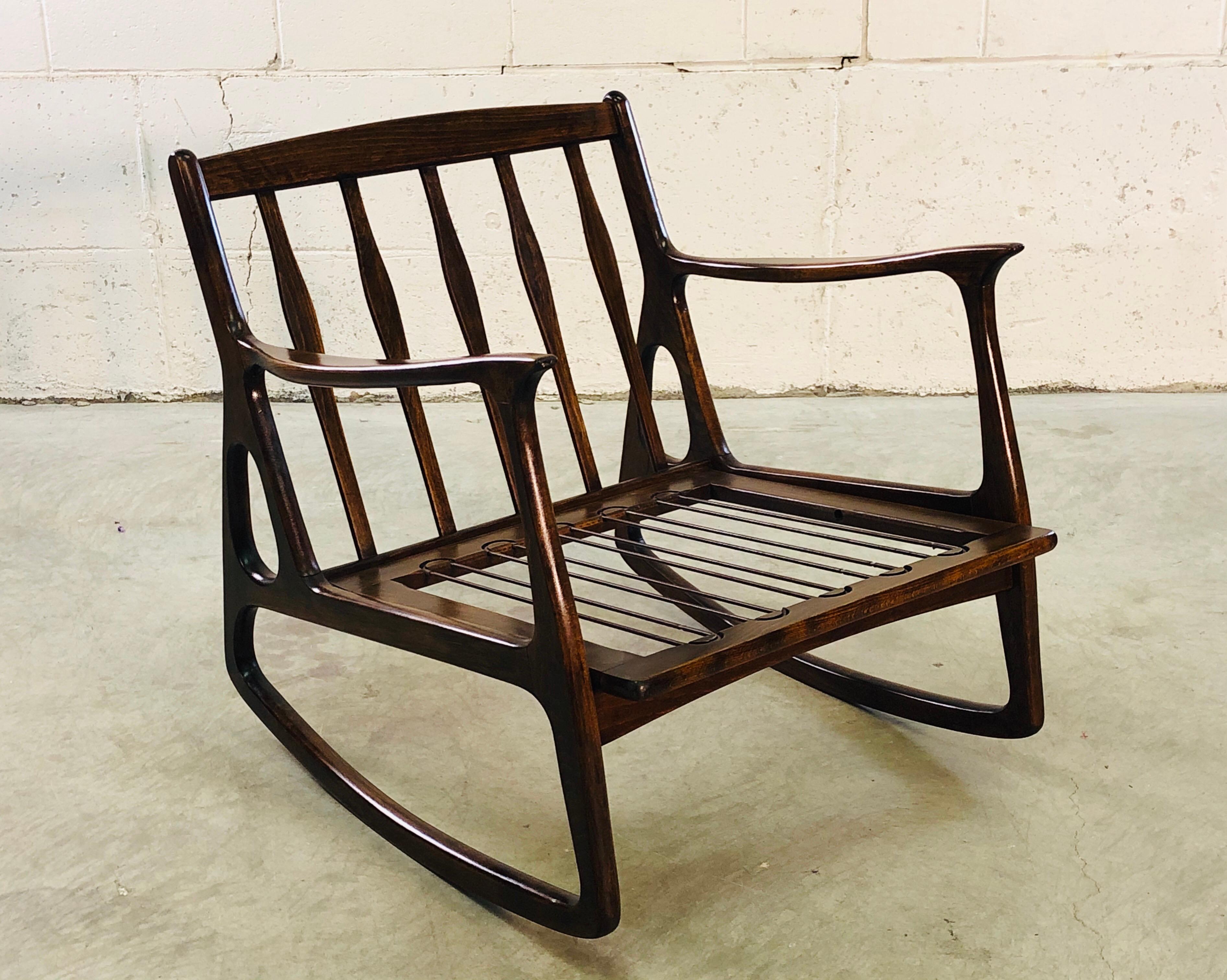 Vintage 1960s Italian dark beechwood rocking chair. The chair has thin, nicely designed arms and is in a dark wood finish. Chair and straps are sturdy, cushions not provided. Marked Italy.