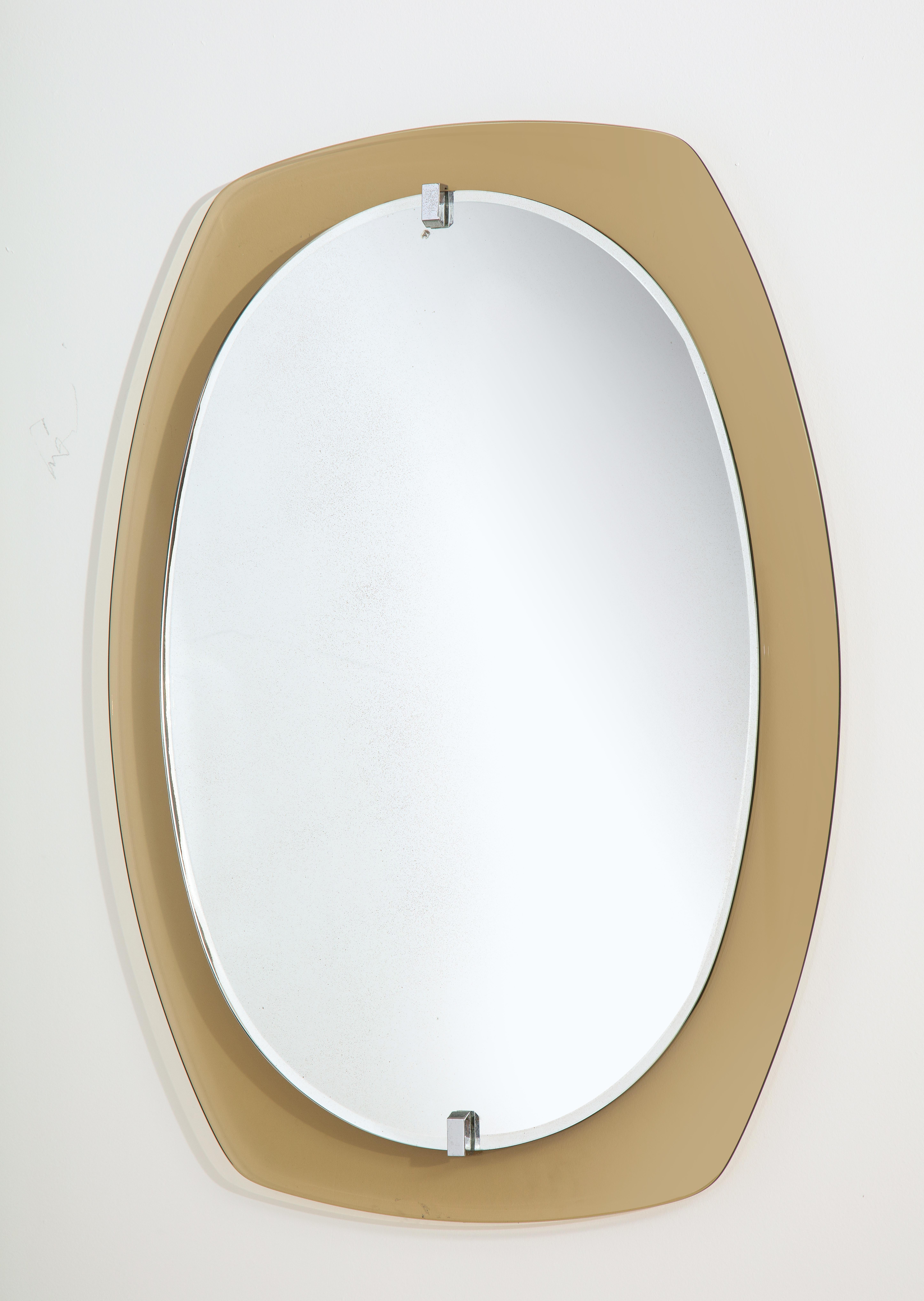 An Italian beveled smoked and clear glass mirror, produced in the 1960's by the famous Italian company Veca. The inner clear glass is raised from the smoked glass border by clasps in nickel-plated brass. making it appear as if it is floating. The