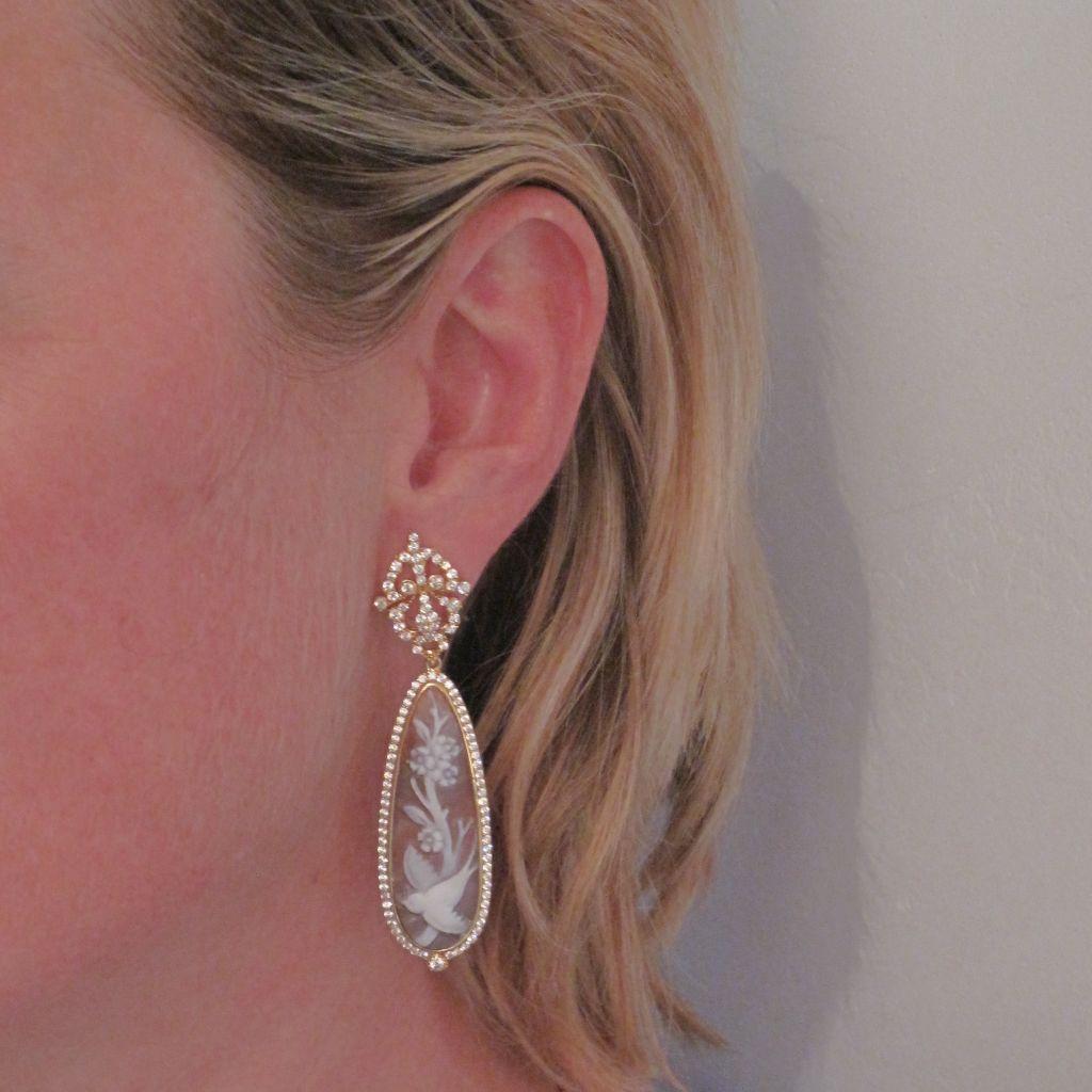 Earrings in vermeil: sterling silver covered with yellow gold.
Each pendant earring consists of a perforated pattern of arabesques and entirely set with small crystals that holds a drop-shaped cameo on shell depicting a branch of flowers and a