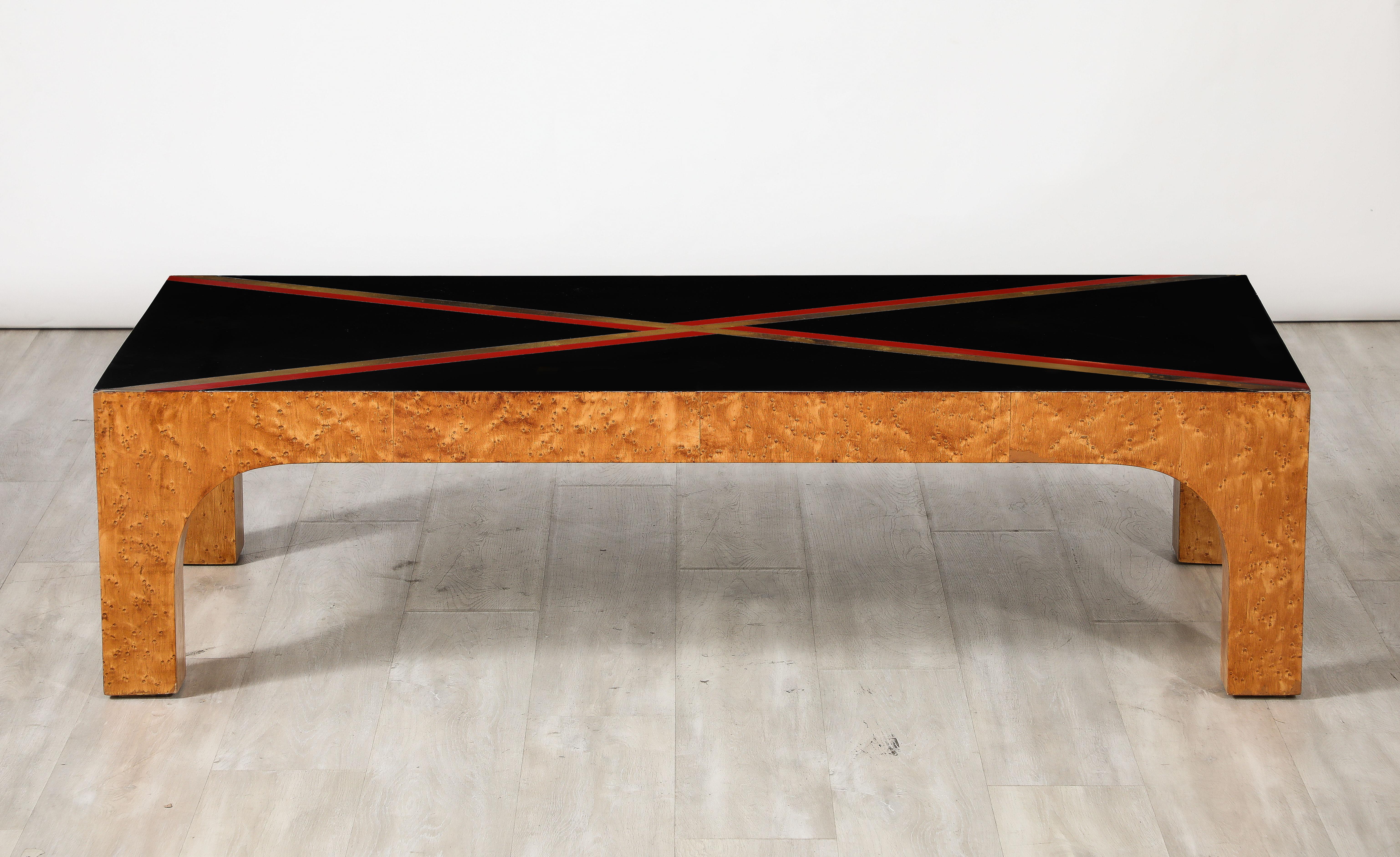 Table basse moderniste italienne aux lignes épurées. Le plateau en verre noir est orné d'une bande de stratifié rouge et métallique en forme de X. Il repose sur des pieds et un tablier en érable à œil d'oiseau.  Le verre et les bandes noires créent