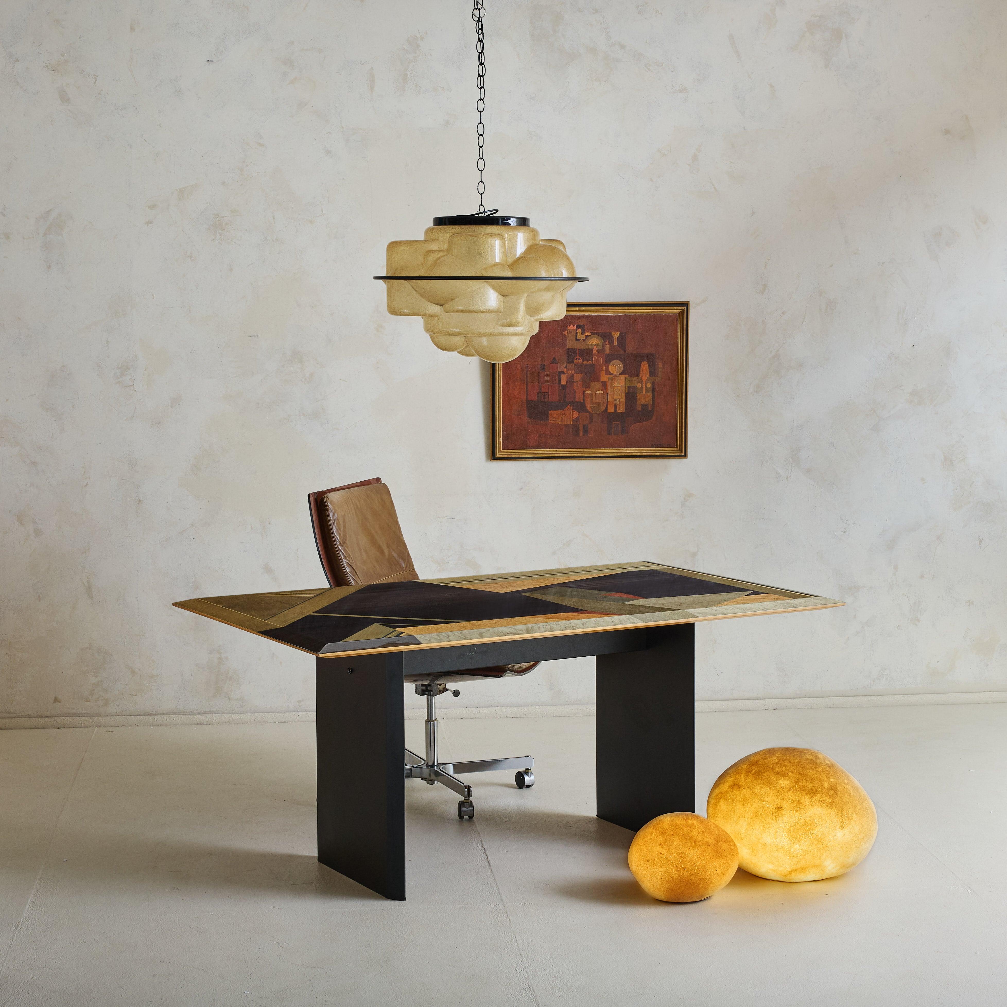 An expression of Postmodern Italian design, this dining table was crafted by Giovanni Offredi for Saporiti in the 1980s. Its surface features a mesmerizing marquetry composition, where angular forms in birdseye maple, ebony-stained wood, and