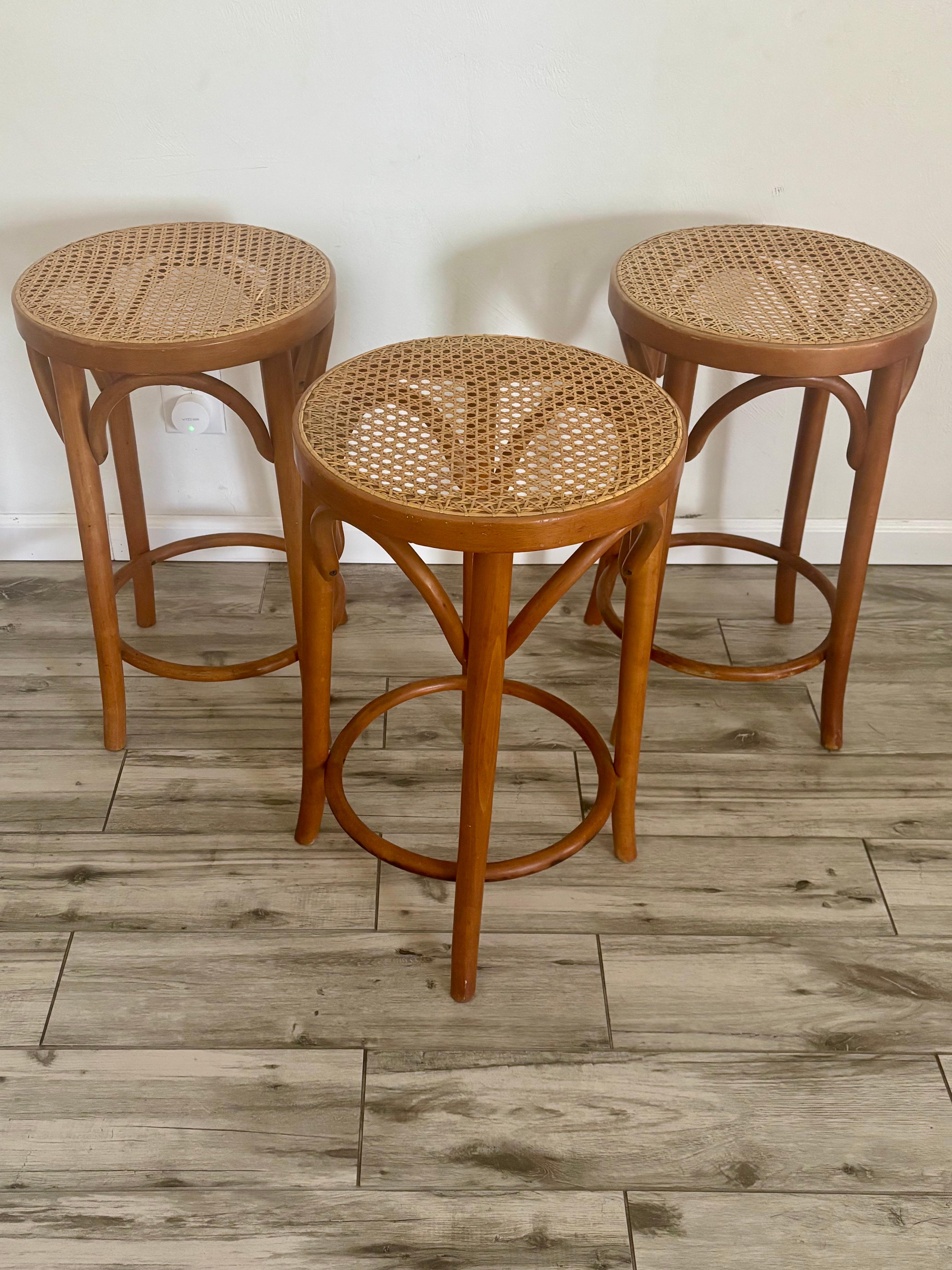 Juego de 3 taburetes de bar estilo bistro italiano riviera. Fabricado en Rumanía en la década de 1950.

Fabricado con madera curvada con precisión y rematado con un asiento de caña. Una interpretación clásica de un taburete. 

Altura de mostrador,