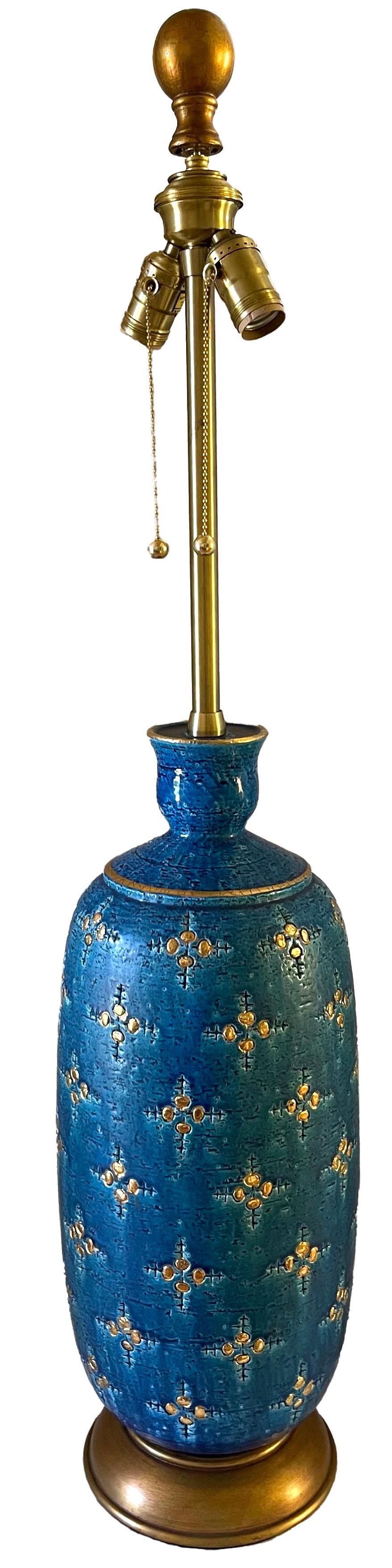 Très grande lampe italienne en céramique bleue et or Bitossi Rimini par Marbro. Corps de lampe en céramique turquoise éblouissante avec des accents dorés peints à la main. Socle original en bois peint en or.
Câblage refait à neuf avec prises en