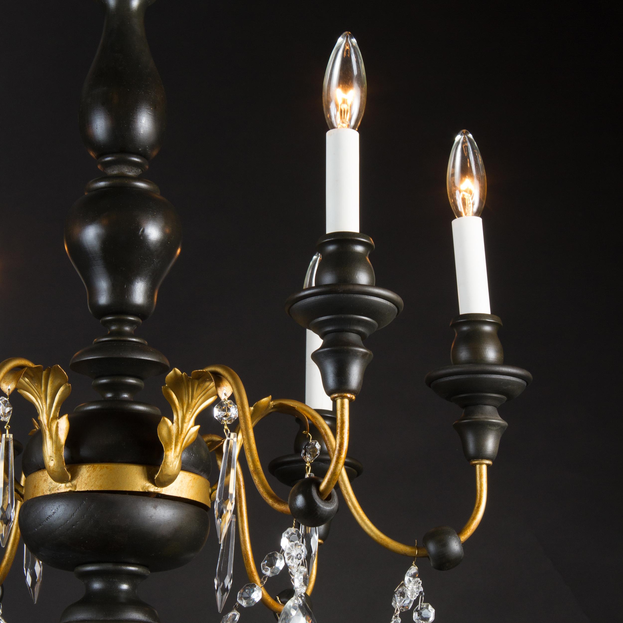 Dating to the mid-20th century, this simple and elegant chandelier is stylistically Louis XVI. Made primarily of wood and draped with crystal, the fixture also has decorative iron and tole elements found at top and on the bases of the arms. The arms
