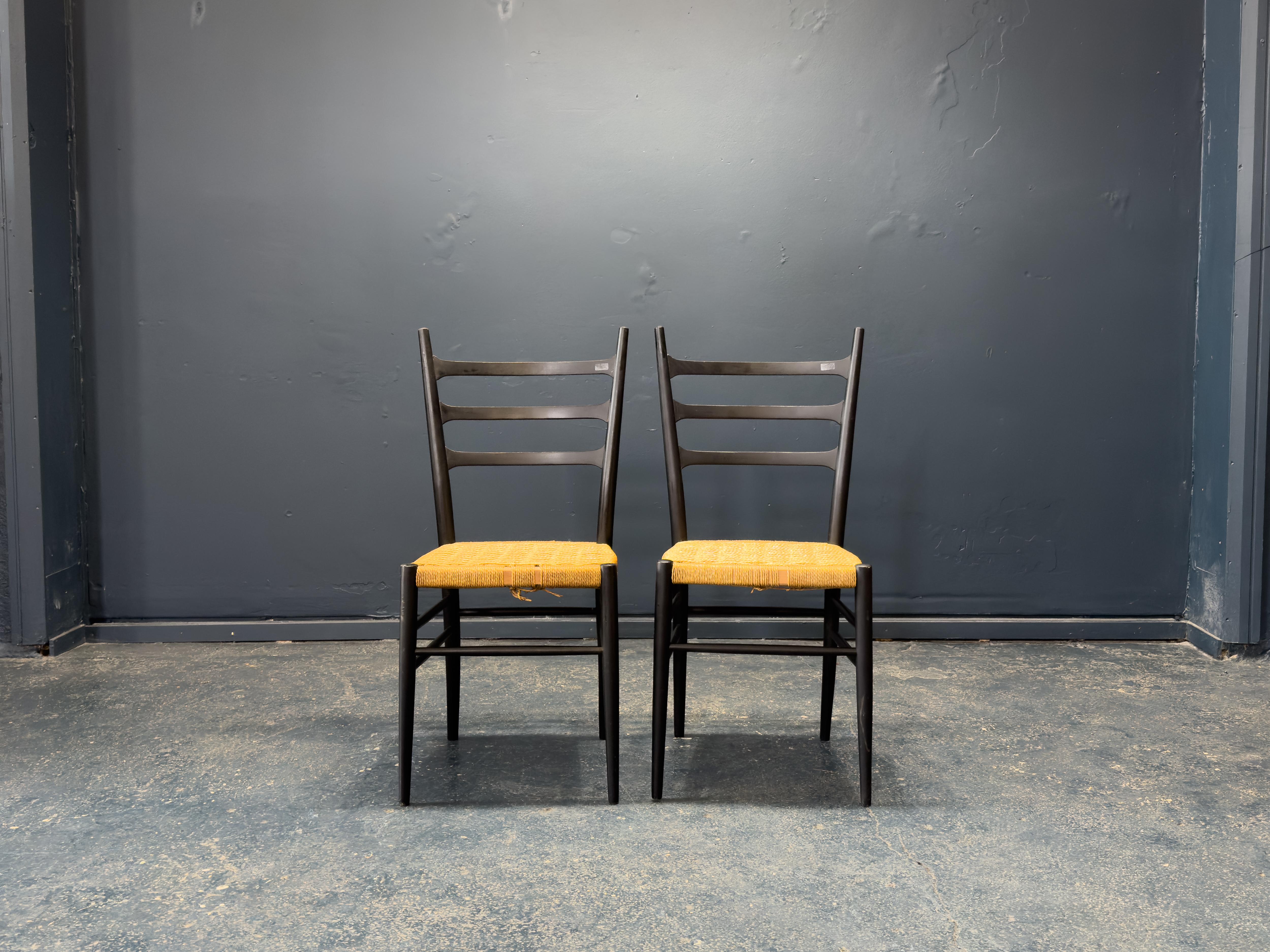 Questa elegante coppia di sedie italiane in seagrass fonde senza sforzo il fascino rustico con il minimalismo raffinato. Le sottili strutture con schienale a scaletta sono realizzate in legno massiccio e rifinite con una ricca tinta scura che