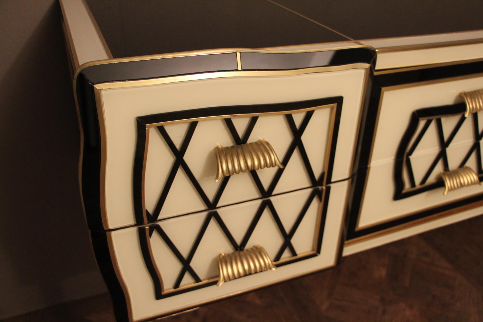 Very refined, this elegant sideboard features an eye-catching geometrical decor made of Murano glass plaques and brass inlay. Black glass segments in relief make crossbars.
It has got 2 deep drawers on each side and 2 long drawers in the middle.