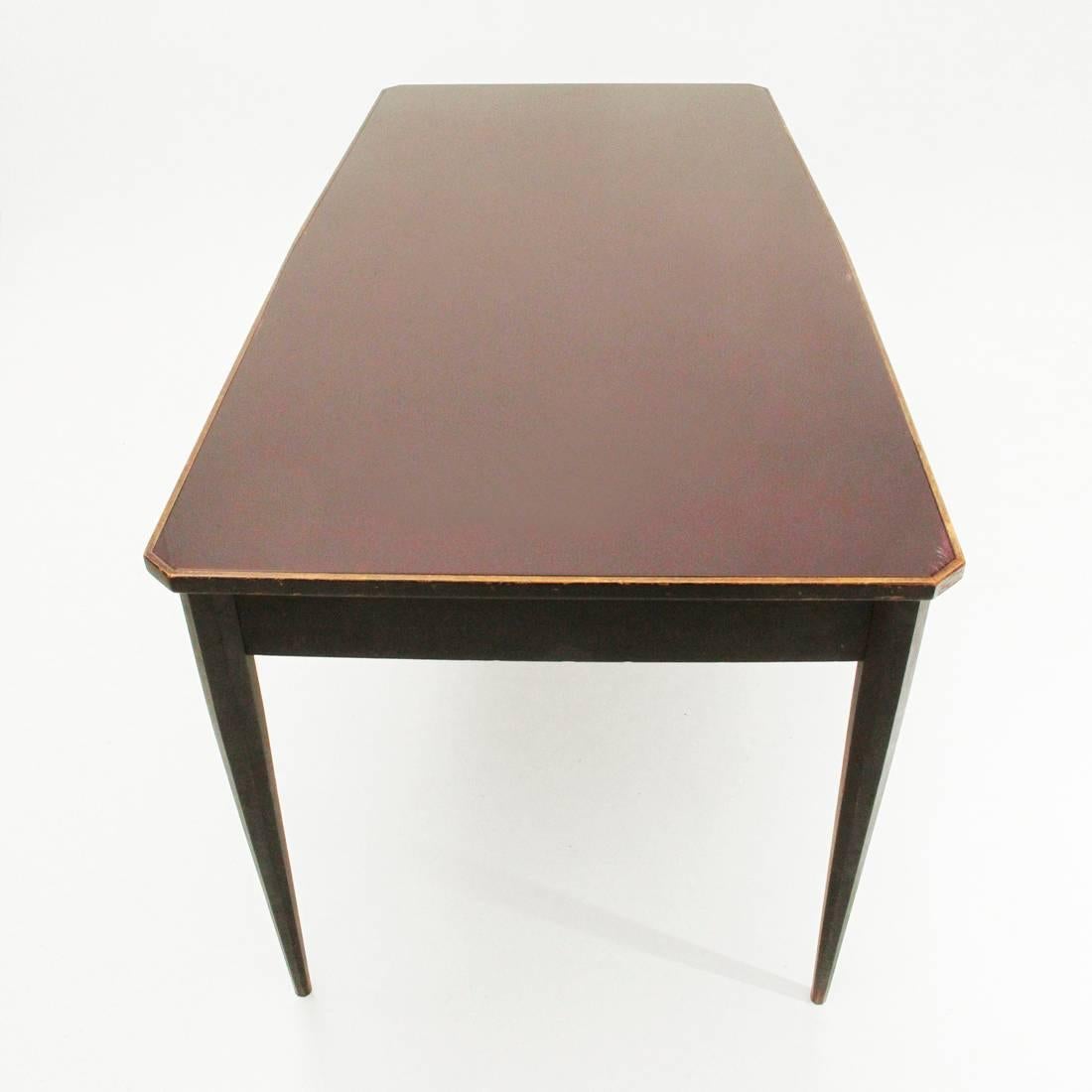 Italian table produced in the 1960s.
Legs and crosspieces in black painted wood.
Top in black painted wood with bordeaux glass top.
Legs of octagonal shape that thins in the final.
Structure in good condition, lack of paint on the edge of the