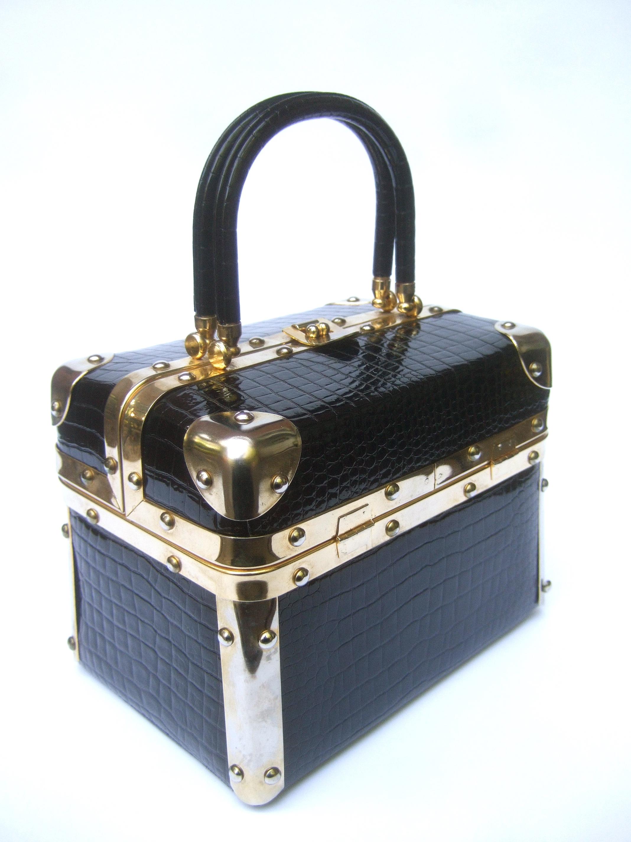 Italian black embossed vinyl box purse designed by Harry Rosenfeld c 1970s
The stylish designer handbag is covered with shiny embossed black vinyl that emulates reptile skin
Framed with sleek gilt metal hardware. Carried with a pair of matching