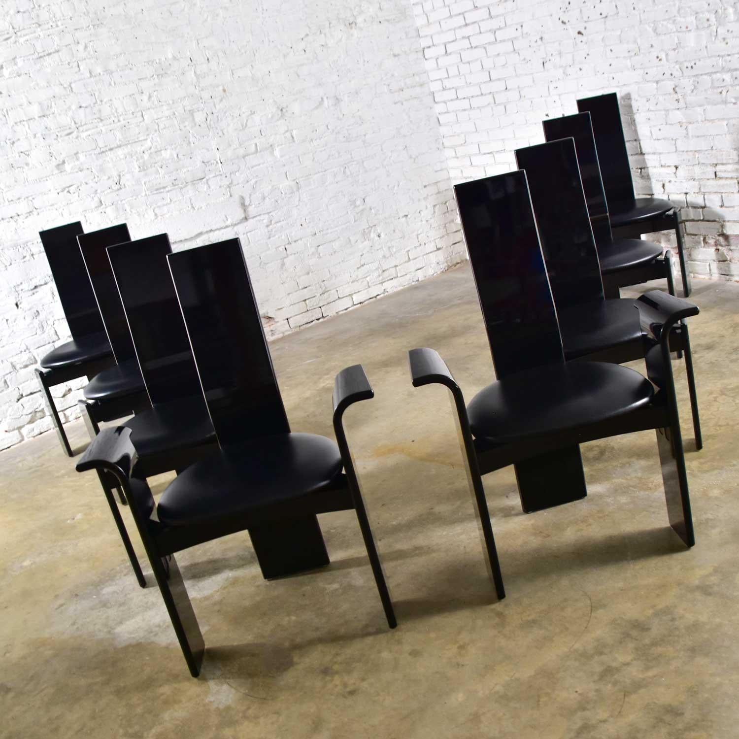 Beautiful set of 8 Italian Postmodern dining chairs attributed to Pietro Costantini. This set includes two armchairs and six side chairs comprised of a black lacquered frame with a tripod style base. Two wide straight front legs, wide back slat that
