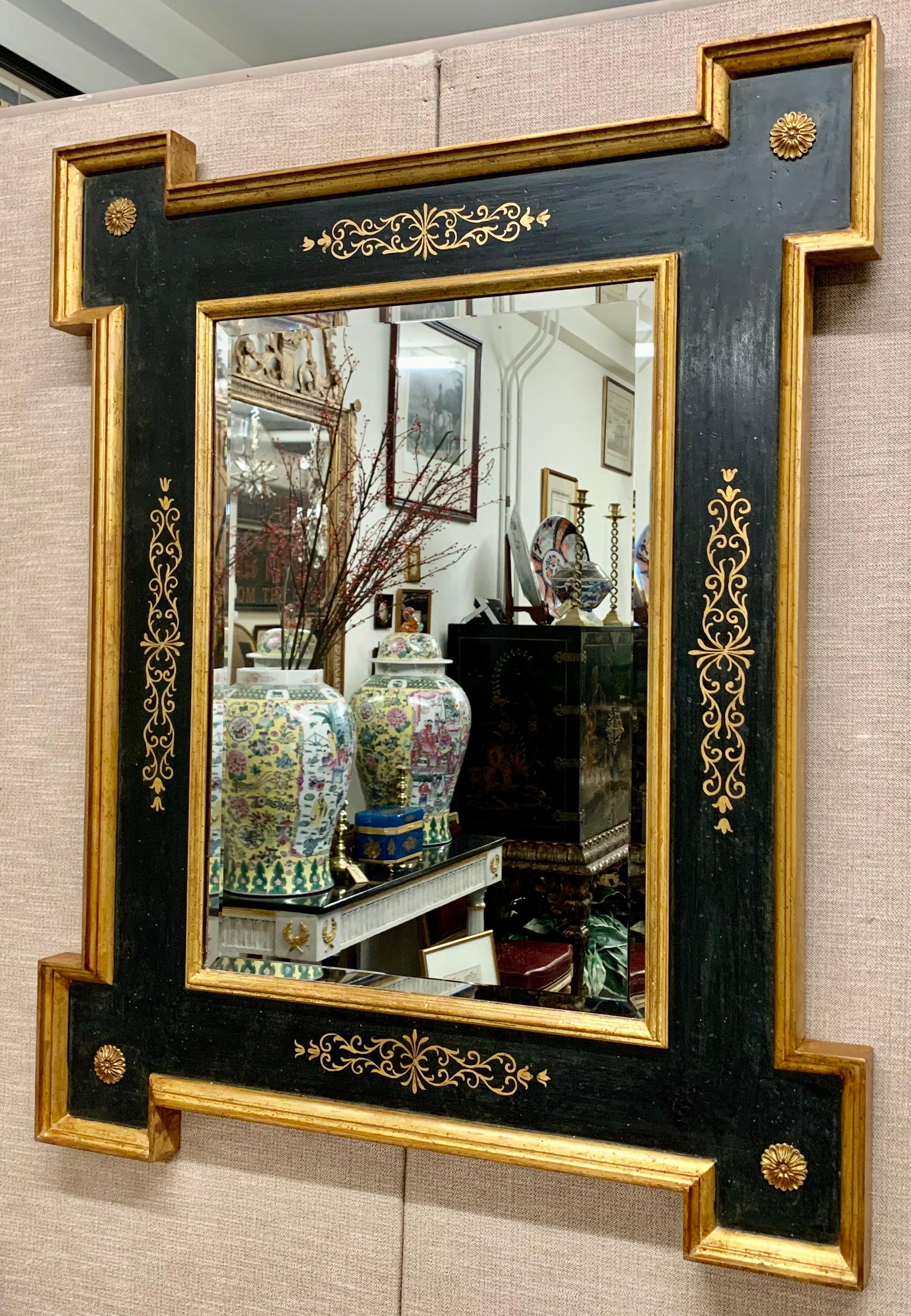 Vintage Italian mirror in black with extended corners and gilt borders. The flat plateau of the mirror has hand painted scrolled designs on all four sides. Each of the extended corners has a centered carved and gilt marguerite flower. The mirror is