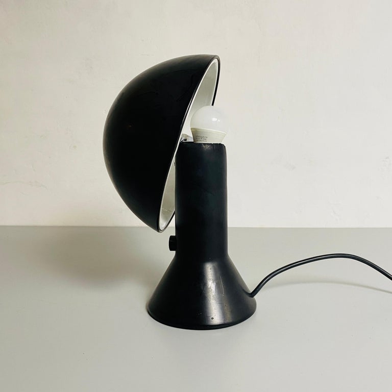 Italian black resin table lamp Elmetto by E.Martinelli for Martinelli Luce, 1976
Black resin table lamp Elmetto, with a conical base and an adjustable hemispherical diffuser with a white painted interior.

Worn plastic near the lamp