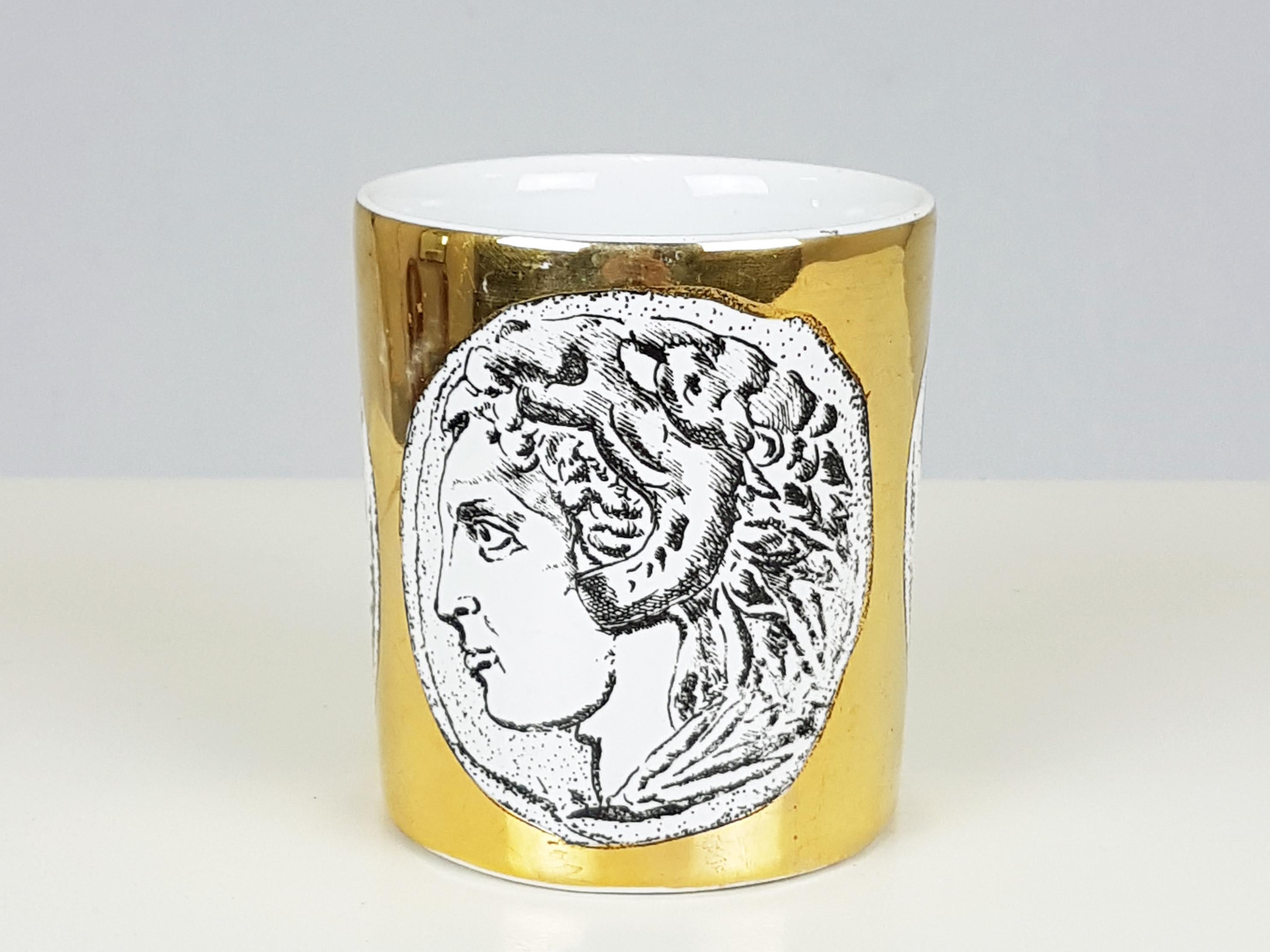 White ceramic cup with black and golden decoration produced in Italy in the manner of Piero Fornasetti. The style of the decoration is classic and is inspired by the profile portraits of ancient numismatics. Pretty good condition: light scratches