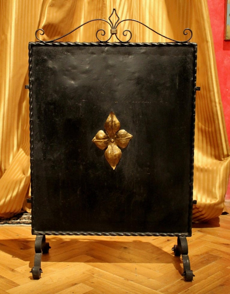 This decorative black wrought iron and parcel-gilt free standing fire screen is a late 19th century Arts & Crafts Florentine artifact. The rectangular panel is flanked by an iron twisted frame throughout and decorated with scrolled iron design on
