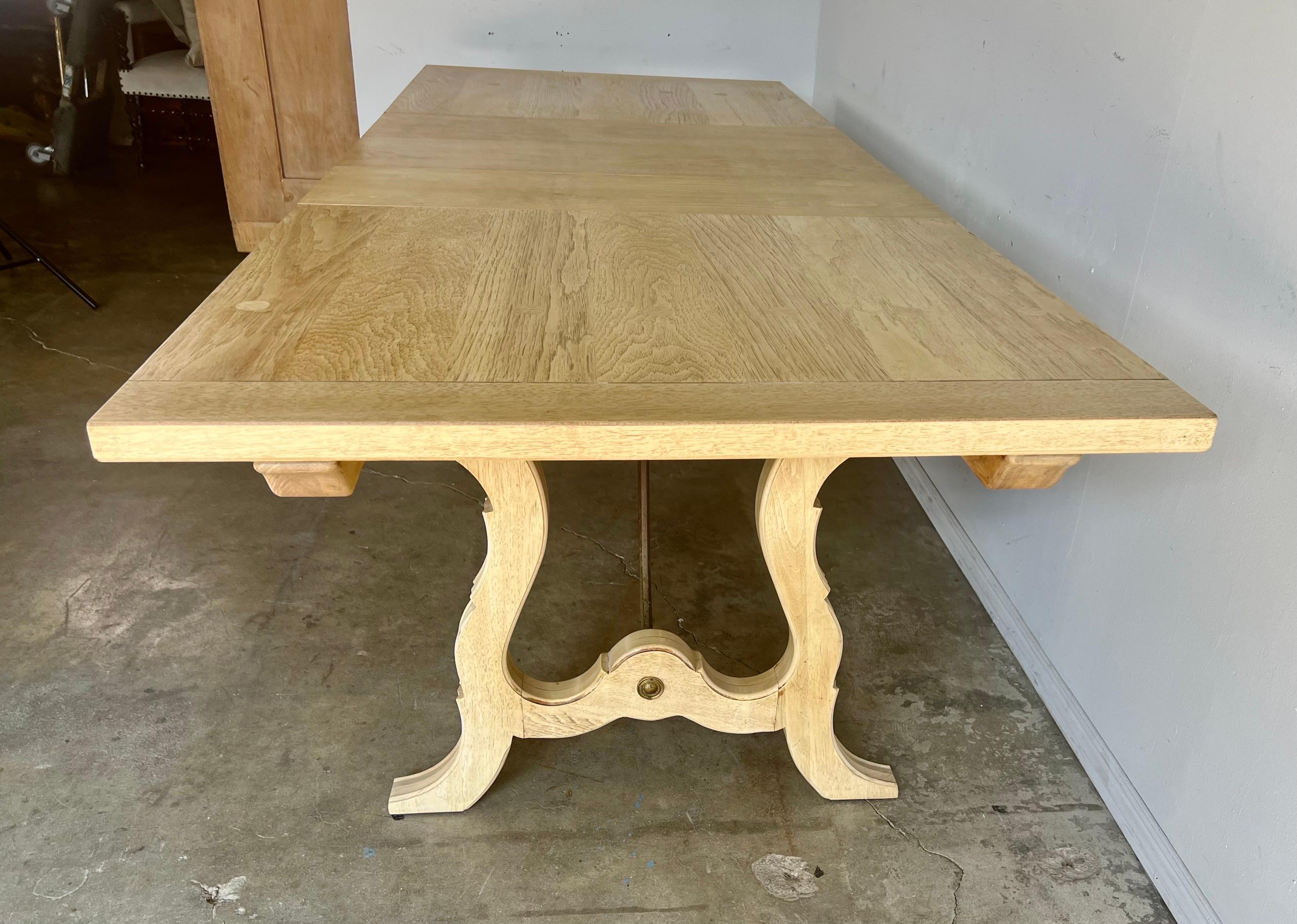 Italian bleached walnut refractory style dining table with two leaves. The table has an iron stretcher that connects both lyre-shaped sides of the table.