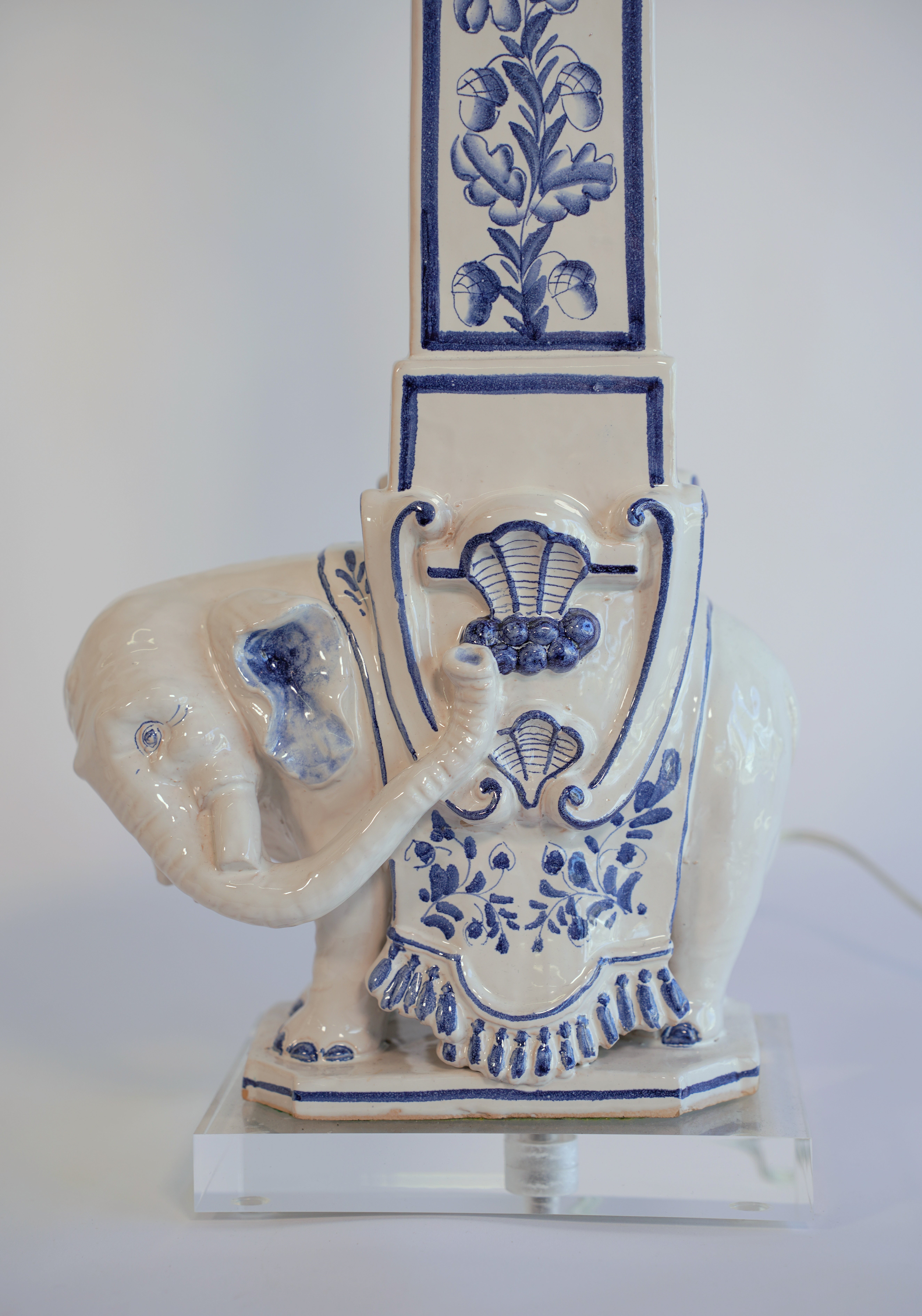 This is a stunning pair of large Italian ceramic table lamps inspired by the Bernini obelisk found in the Piazza di Minerva, Rome. The midcentury blue and white pottery features a well-sculptured Indian elephant supporting a tall obelisk with