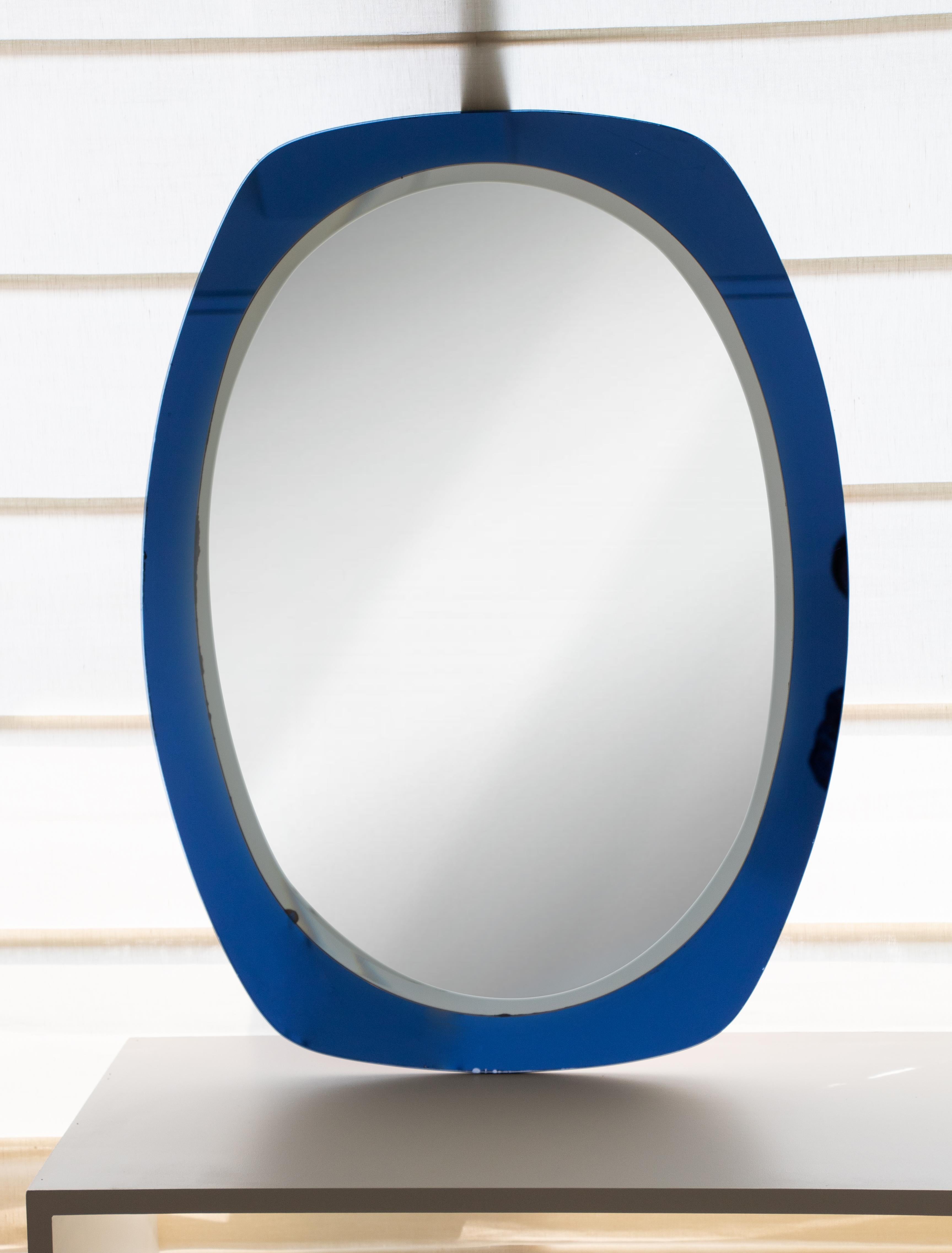 Vintage Italian blue glass mirror from the 1950s. Vibrant colored blue glass frame with oval mirror layered on top. Beautiful piece for a bathroom or entry way. 

  