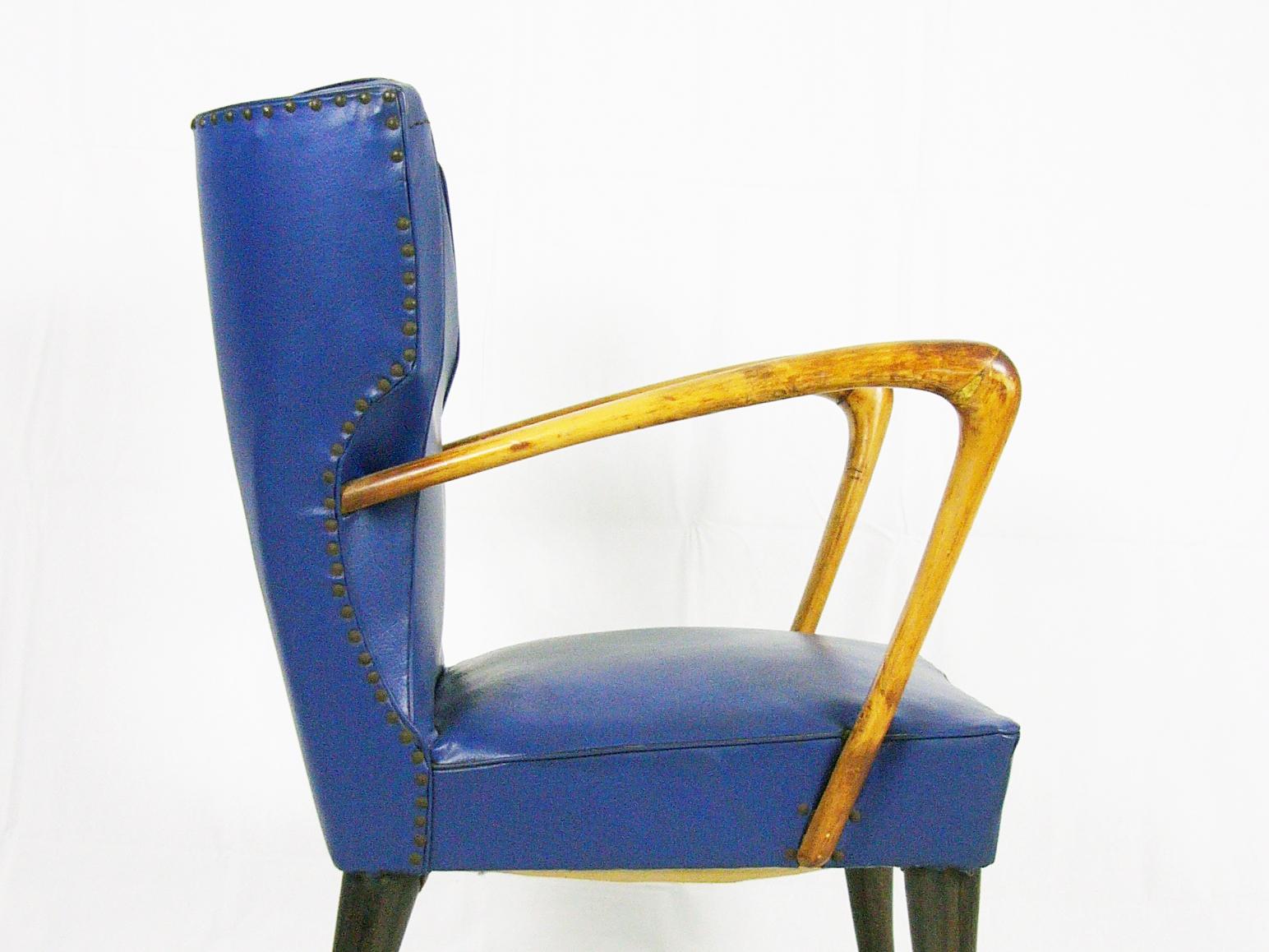Ce fauteuil a été produit en Italie au début des années 1950. Il est constitué d'une structure en bois avec un accoudoir sculptural et des pieds marron foncé. Le fauteuil est recouvert de skaï bleu. Les conditions extérieures sont bonnes, mais le
